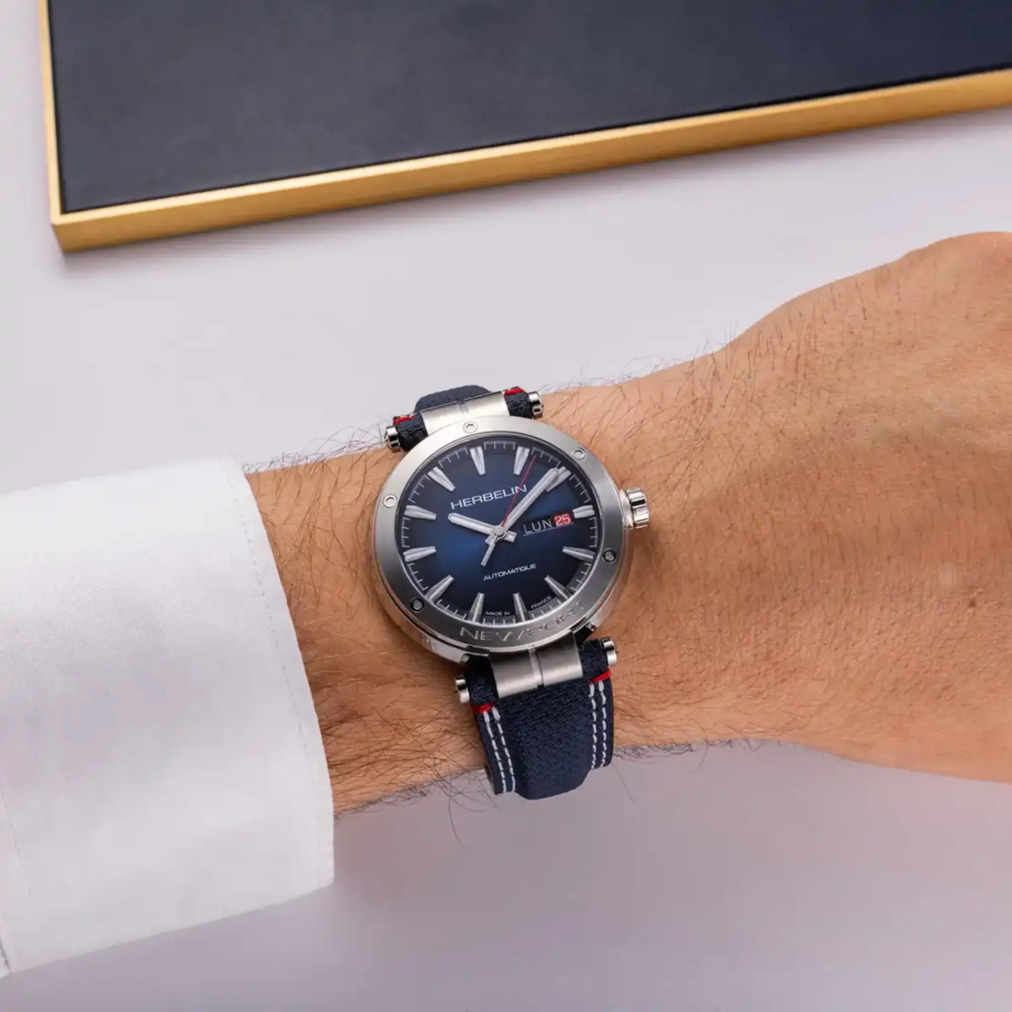 Au poignet masculin, cadran dégradé noir bleu et bracelet textile visibles