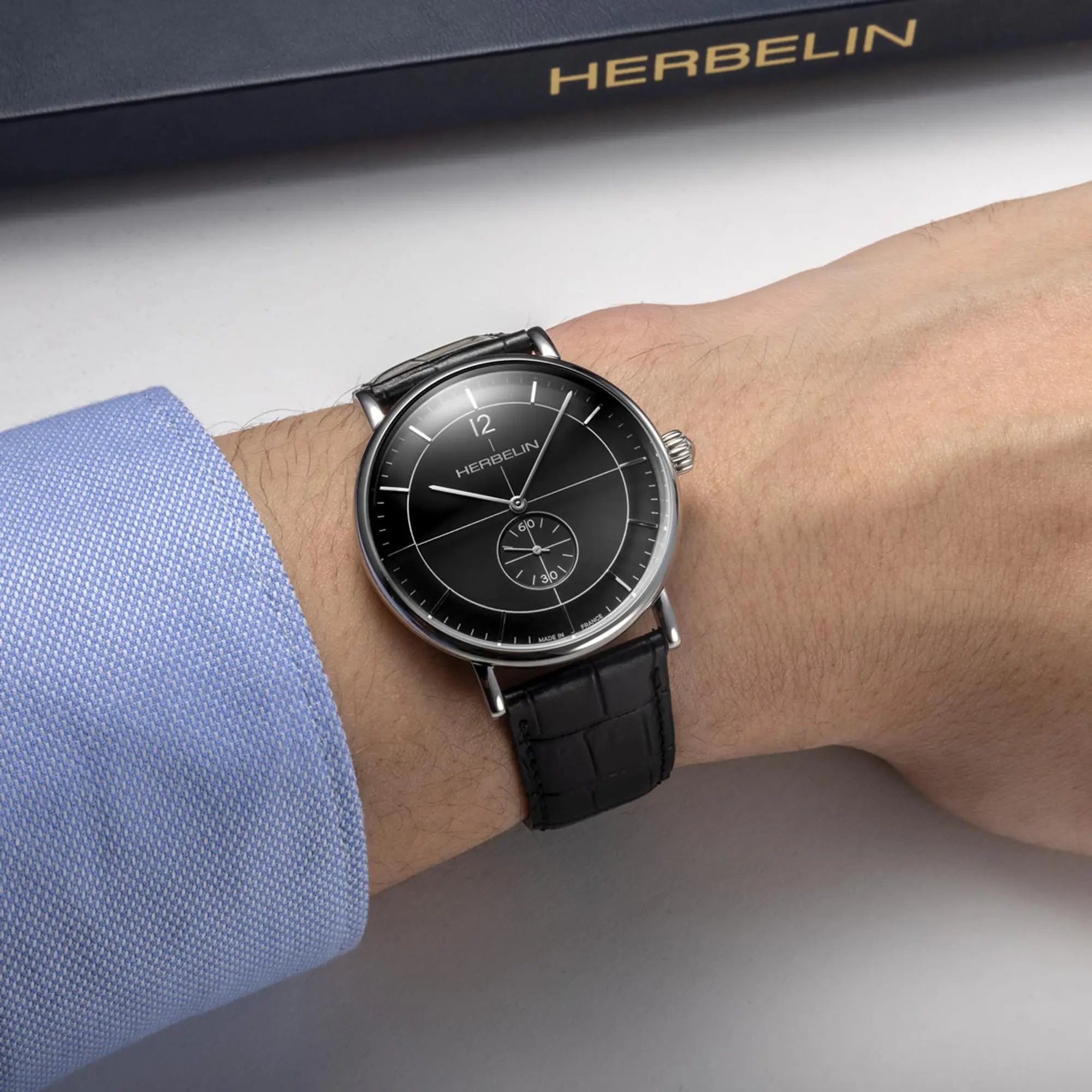 Au poignet masculin, cadran noir et bracelet cuir visibles