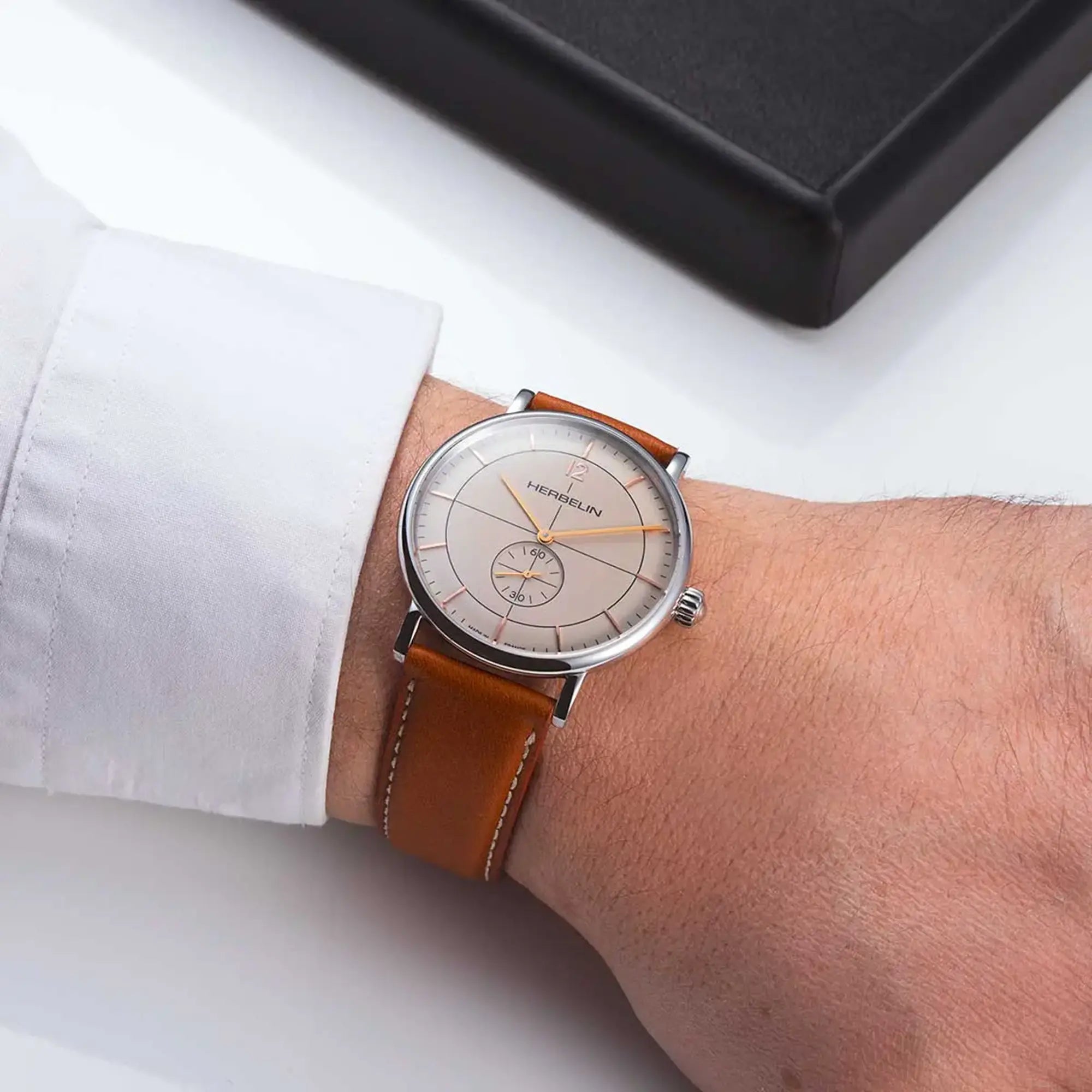 Au poignet masculin, cadran coquille d'œuf et bracelet cuir visibles