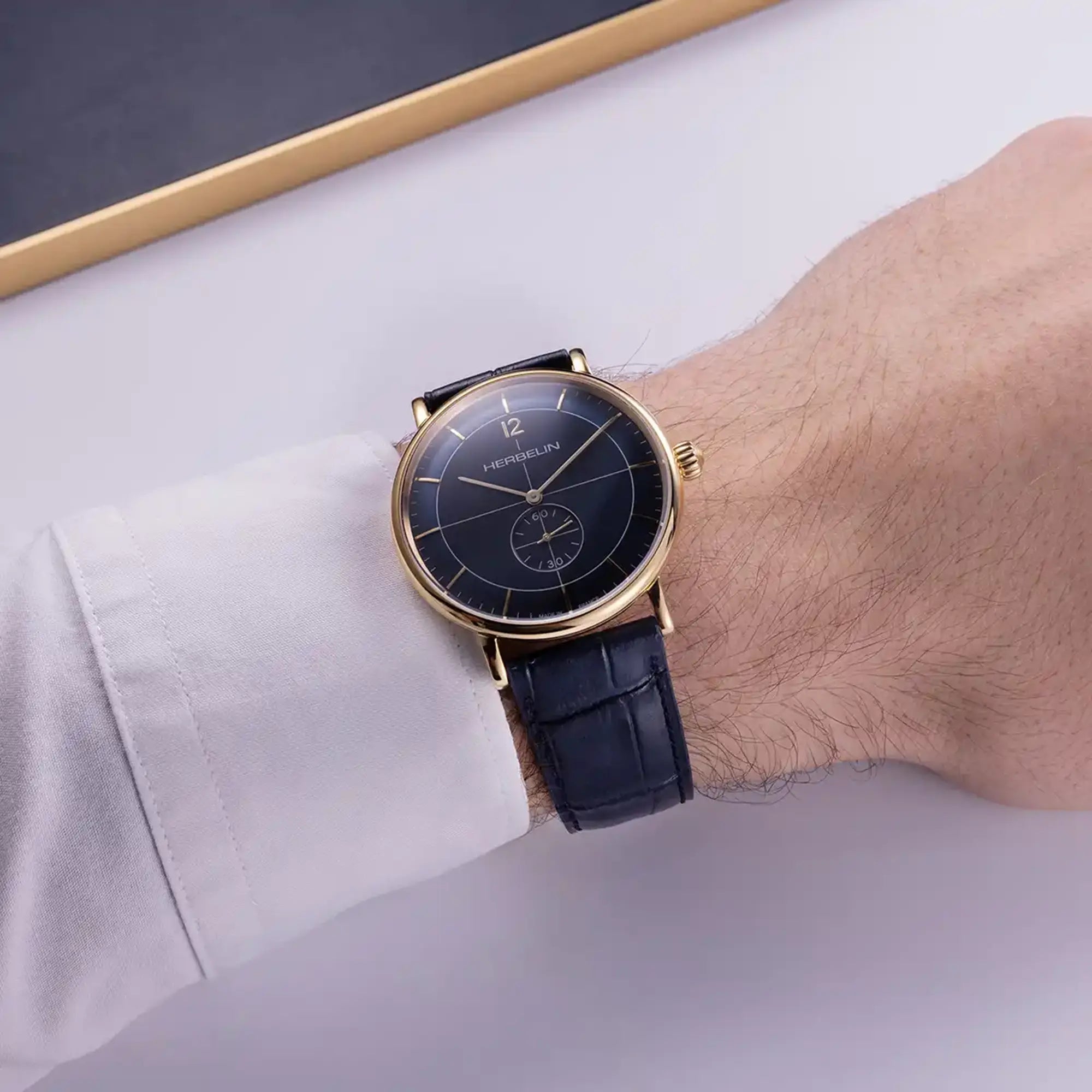 Au poignet masculin, cadran bleu et bracelet cuir visibles