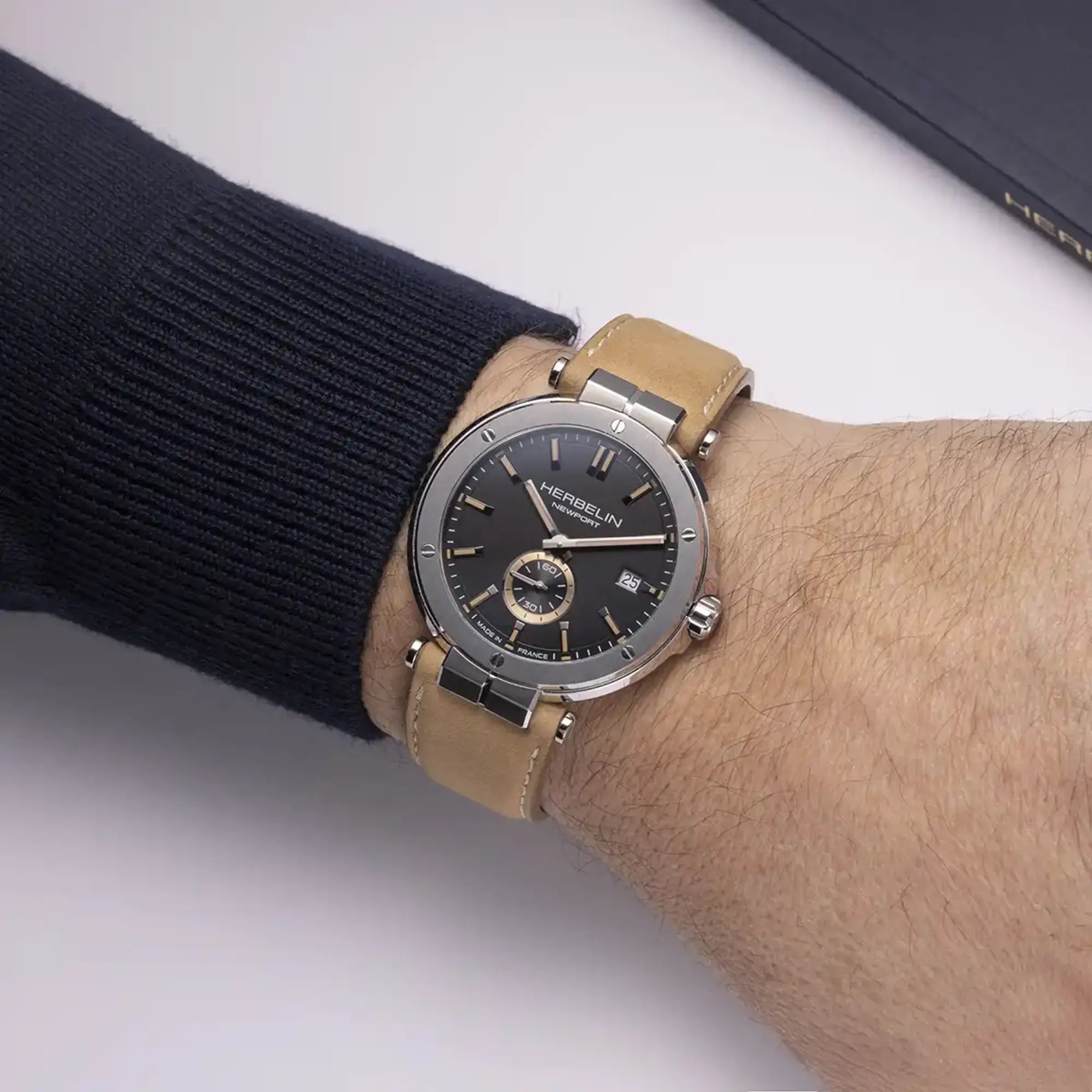 Au poignet masculin, cadran noir mat et bracelet cuir visibles