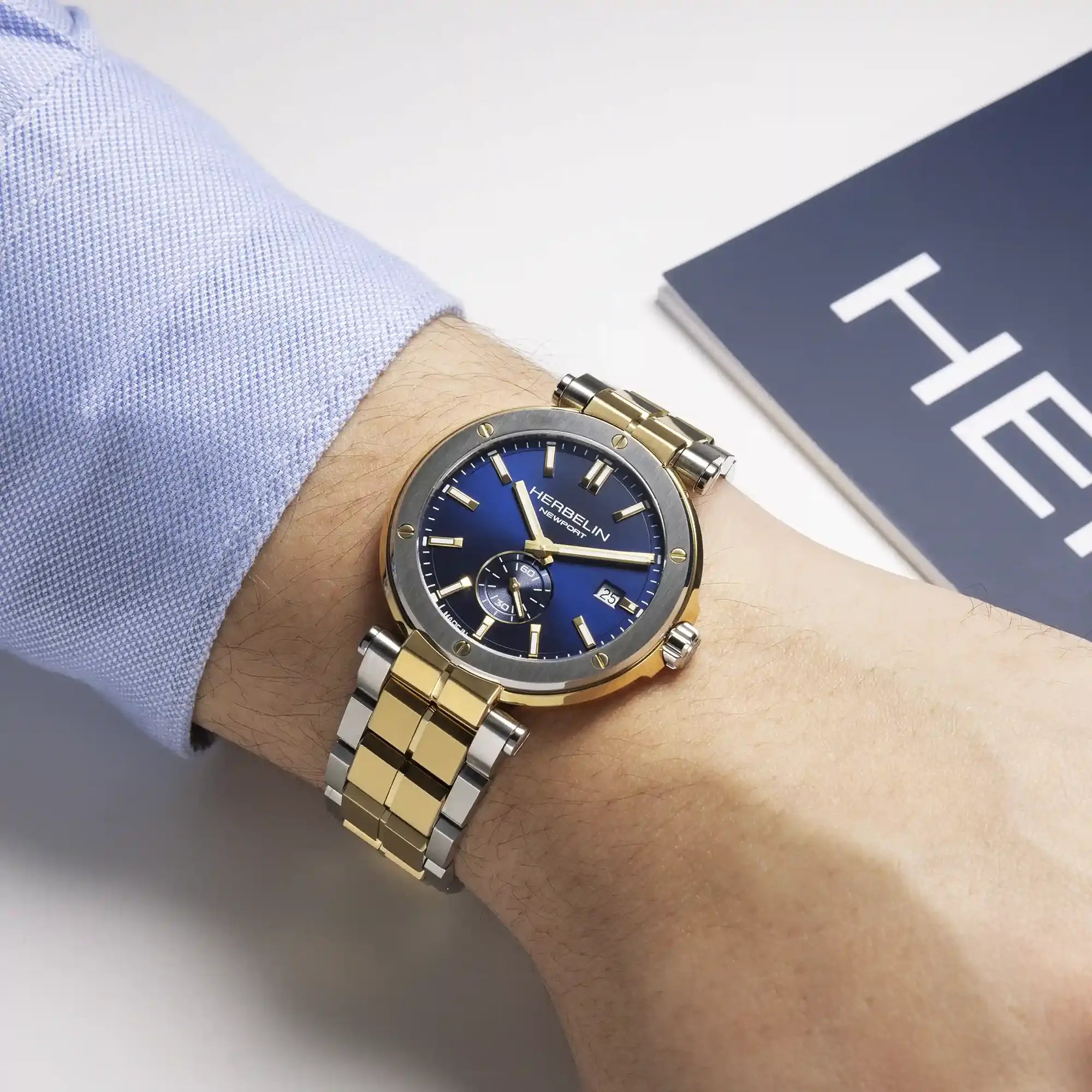 Au poignet masculin, cadran bleu et bracelet acier bicolore visibles