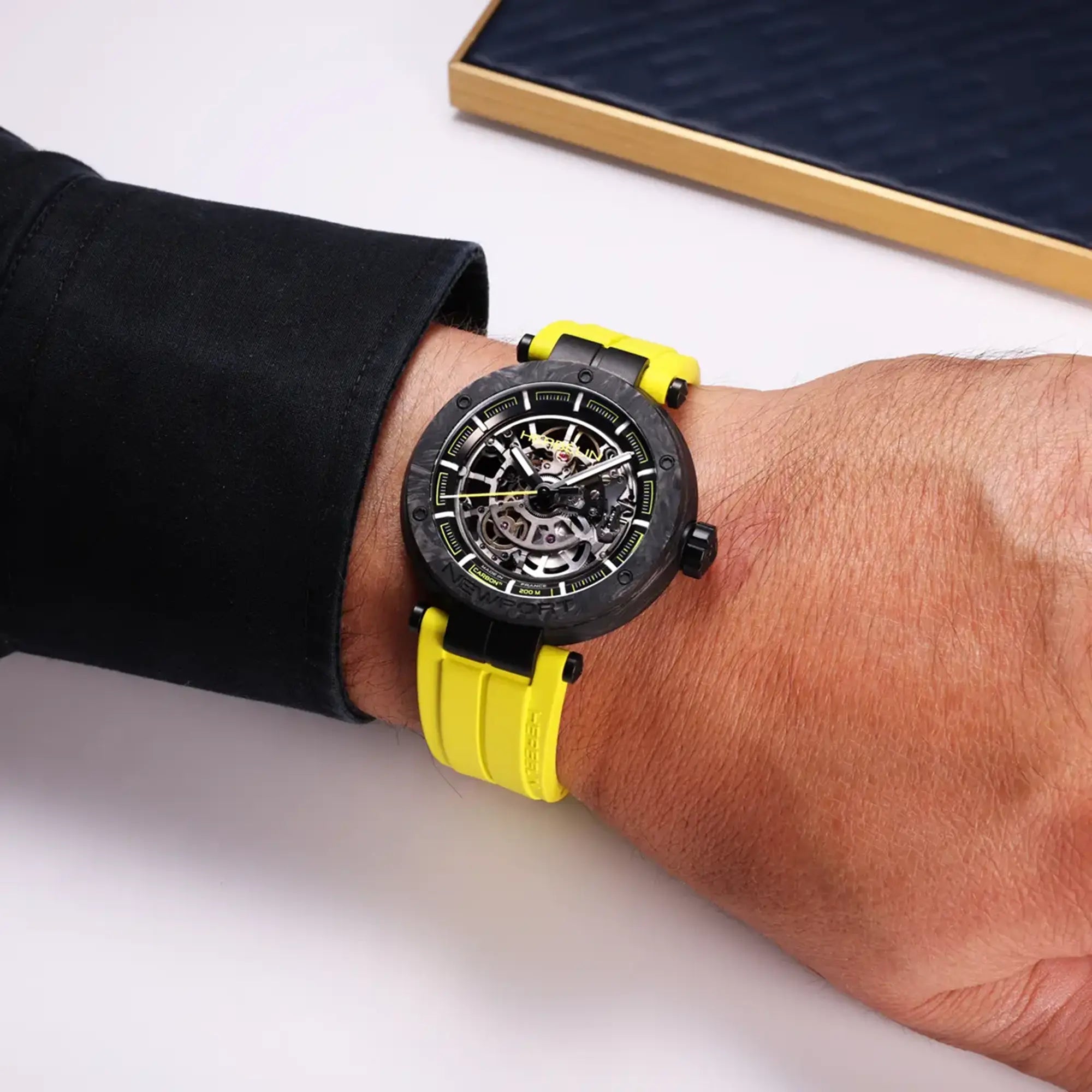 Au poignet masculin, cadran noir et bracelet caoutchouc visibles