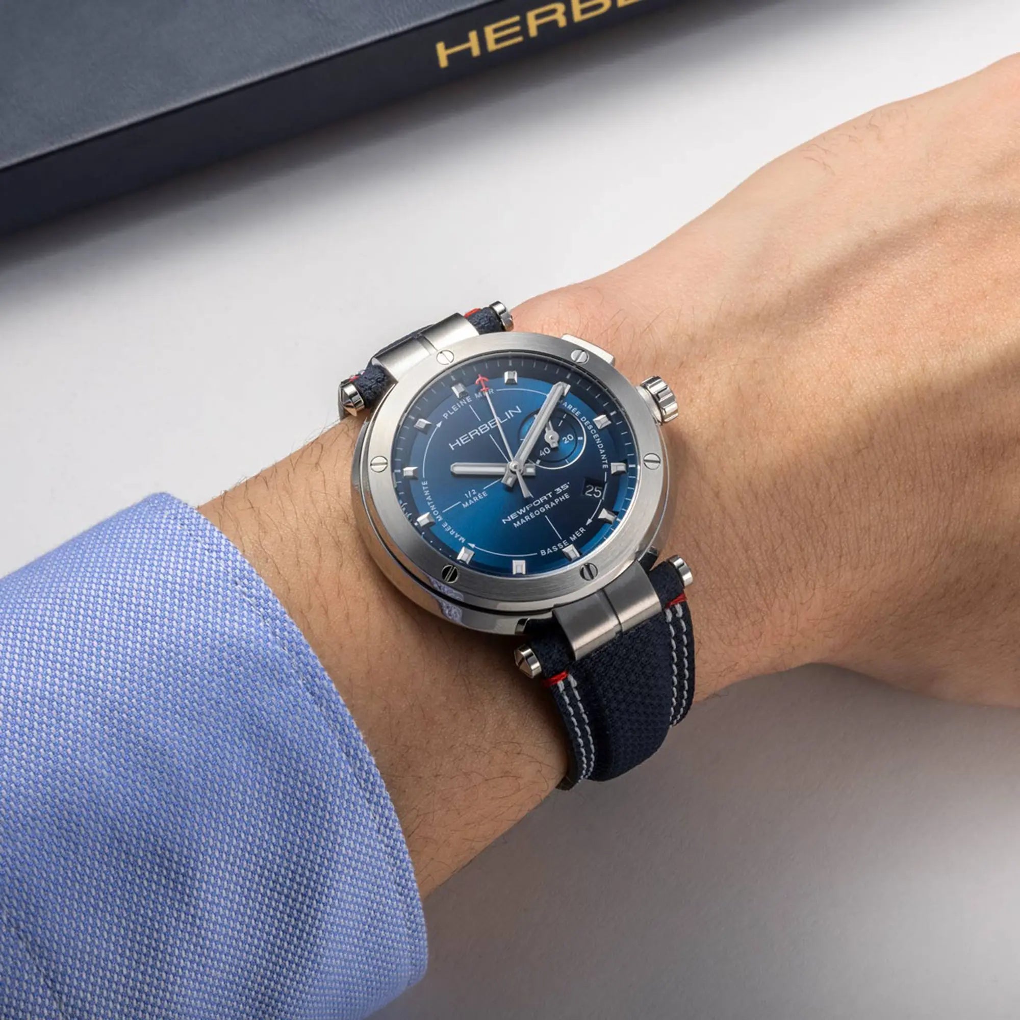 Au poignet masculin, cadran bleu et bracelet textile visibles