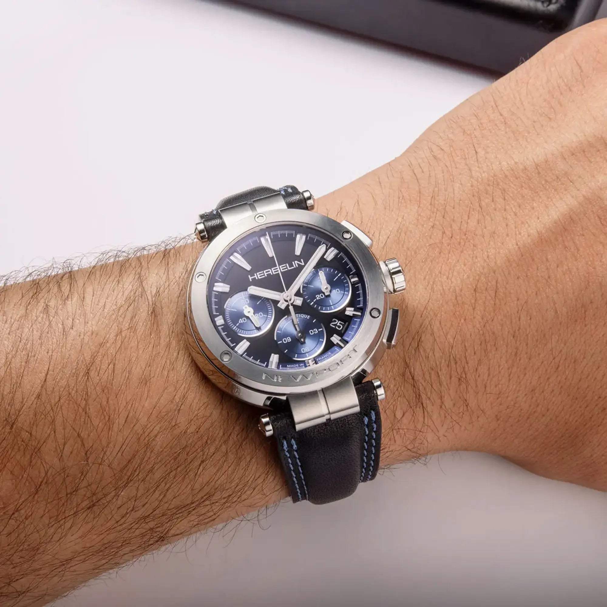 Au poignet masculin, cadran noir mat et bracelet cuir visibles