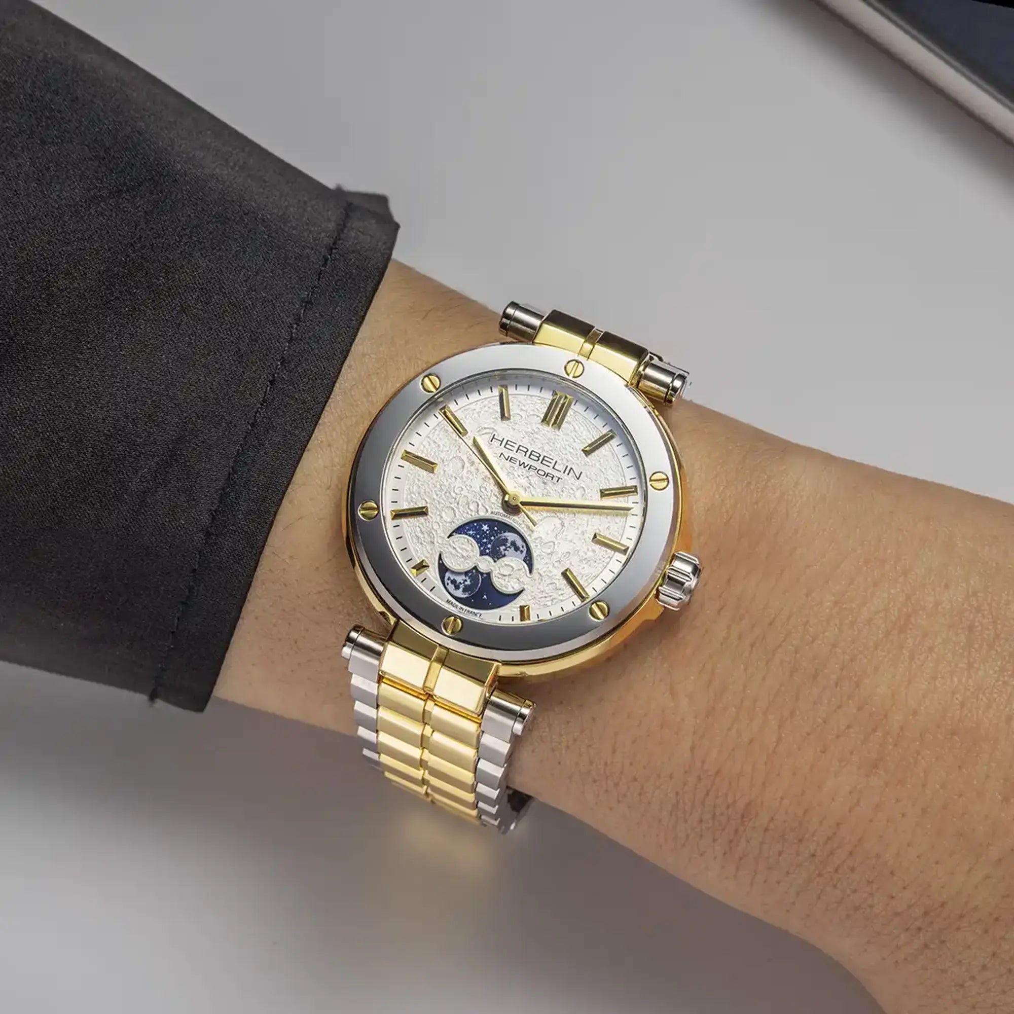 Au poignet féminin, cadran décor lunaire et bracelet acier bicolore visibles