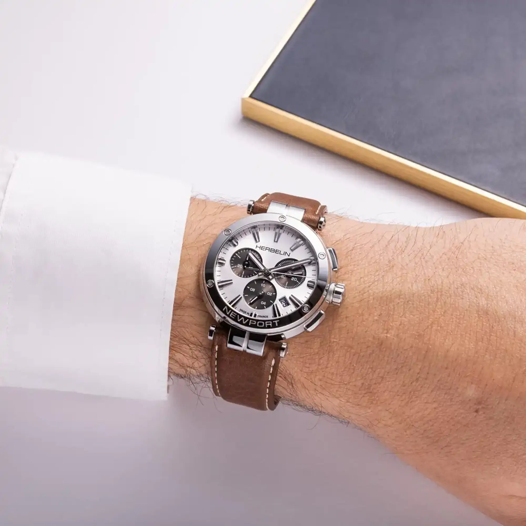 Au poignet masculin, cadran argent blanc et bracelet cuir visibles