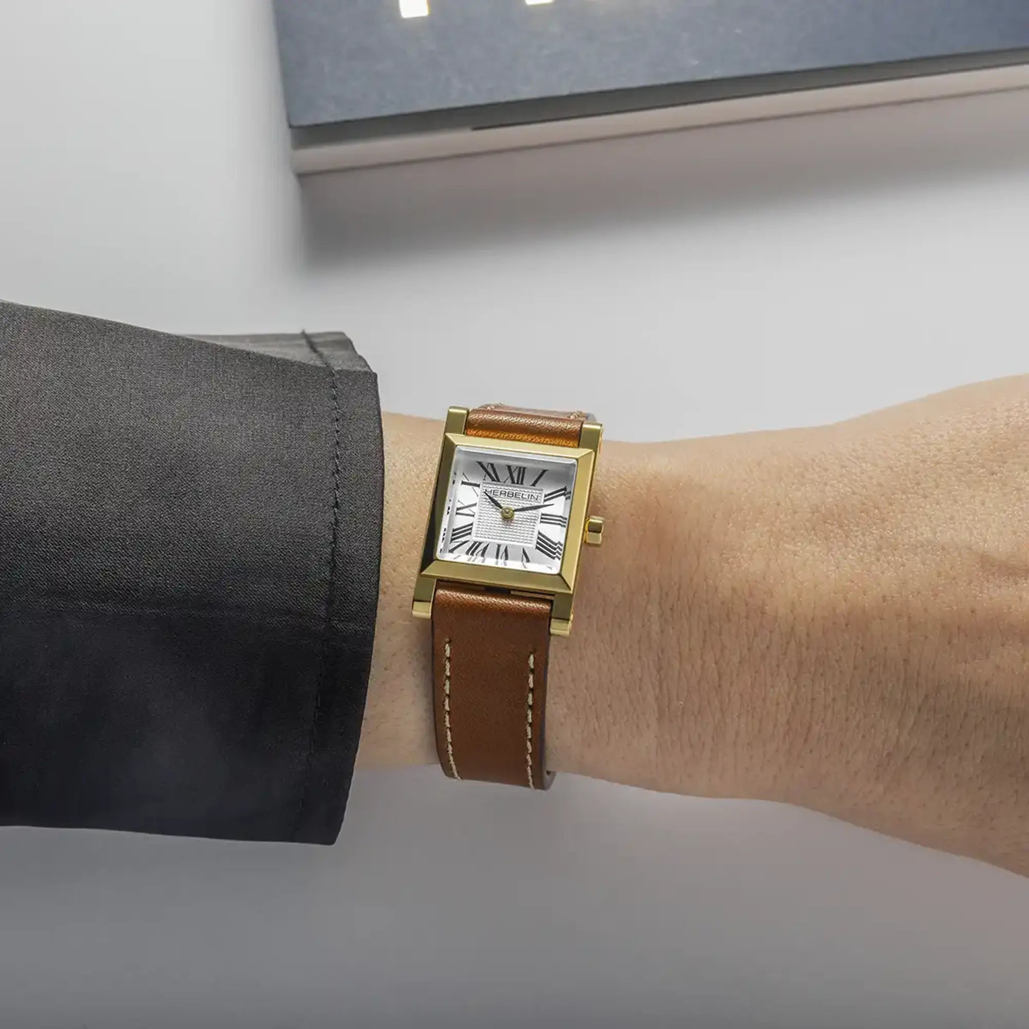 Au poignet féminin, cadran argent guilloché et bracelet cuir visibles