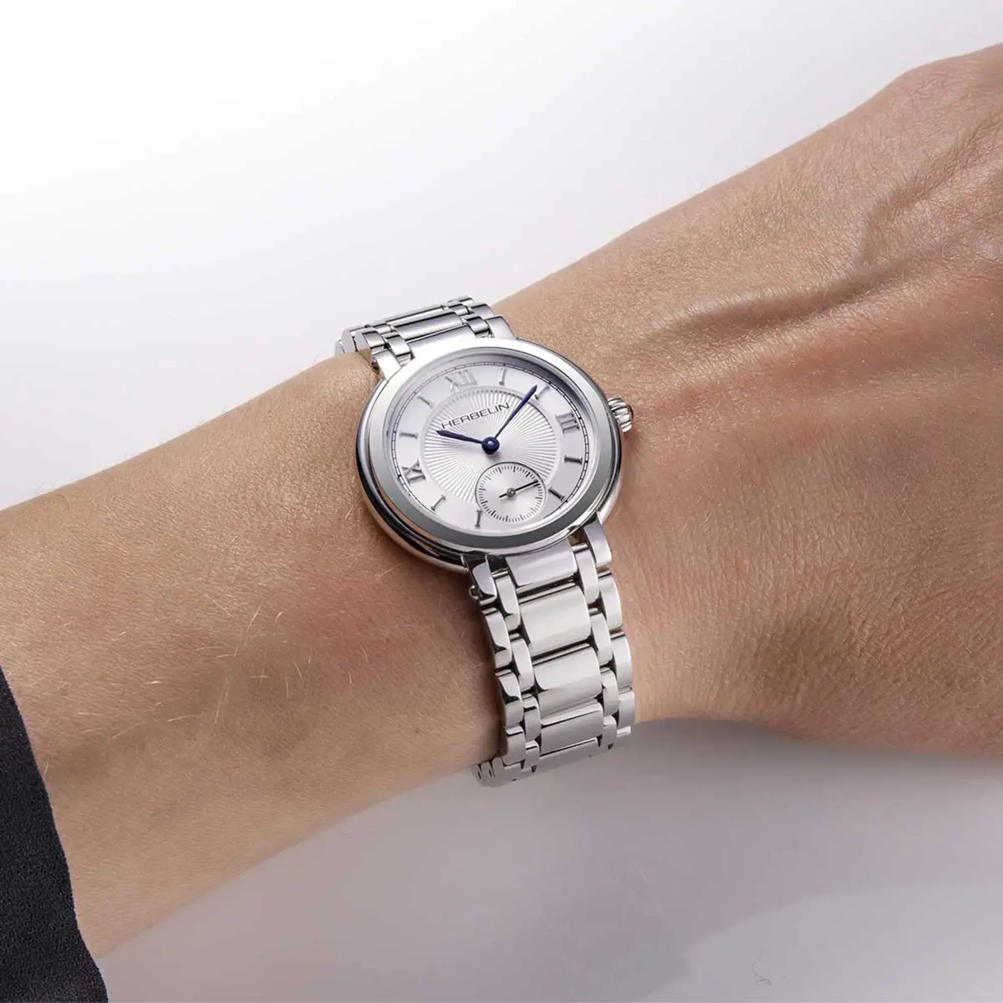 Au poignet féminin, cadran argent guilloché et bracelet acier visibles
