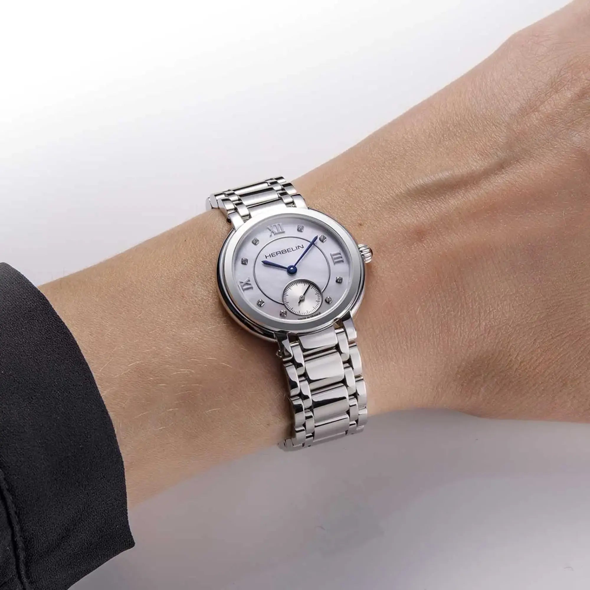 Au poignet féminin, cadran nacre blanche et bracelet acier visibles