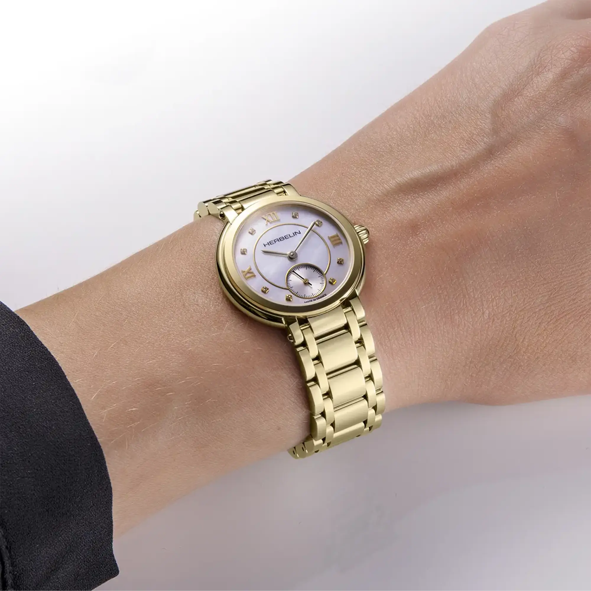 Au poignet féminin, cadran nacre blanche et bracelet acier bicolore visibles