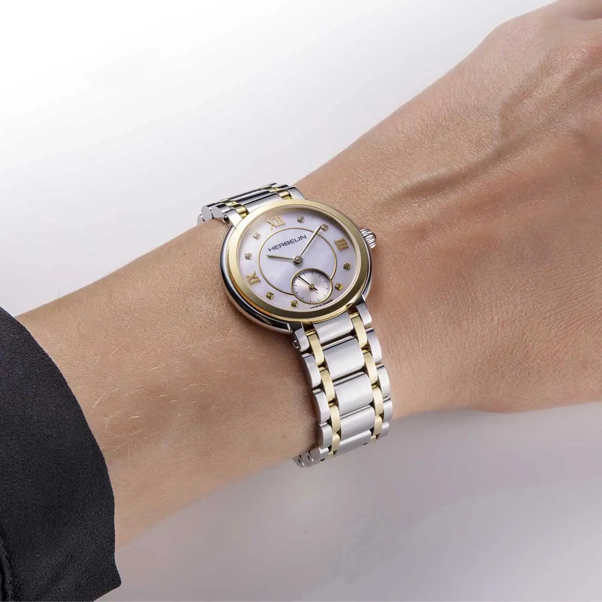 Au poignet féminin, cadran nacre blanche et bracelet acier bicolore visibles