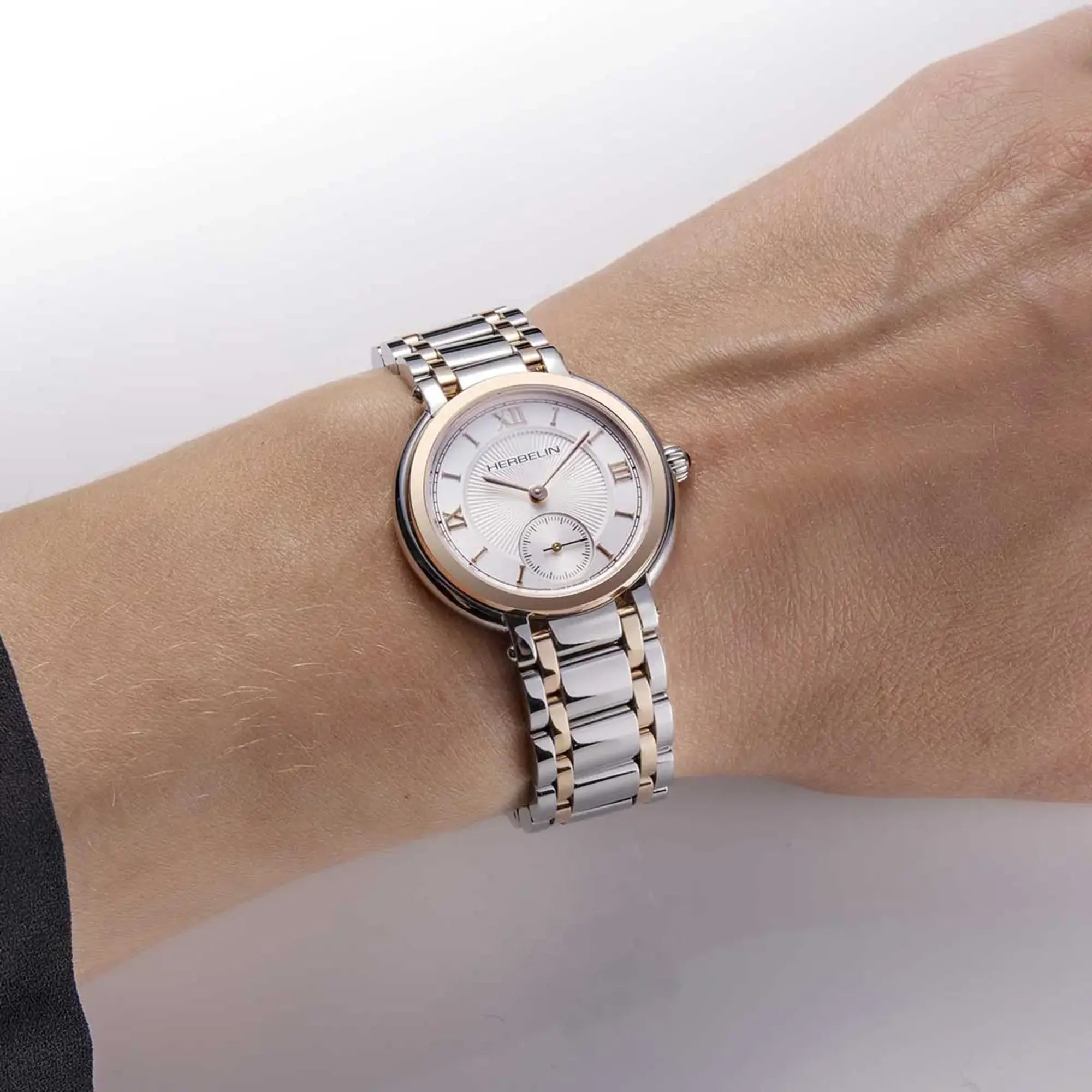 Au poignet féminin, cadran argent guilloché et bracelet acier PVD or rose visibles