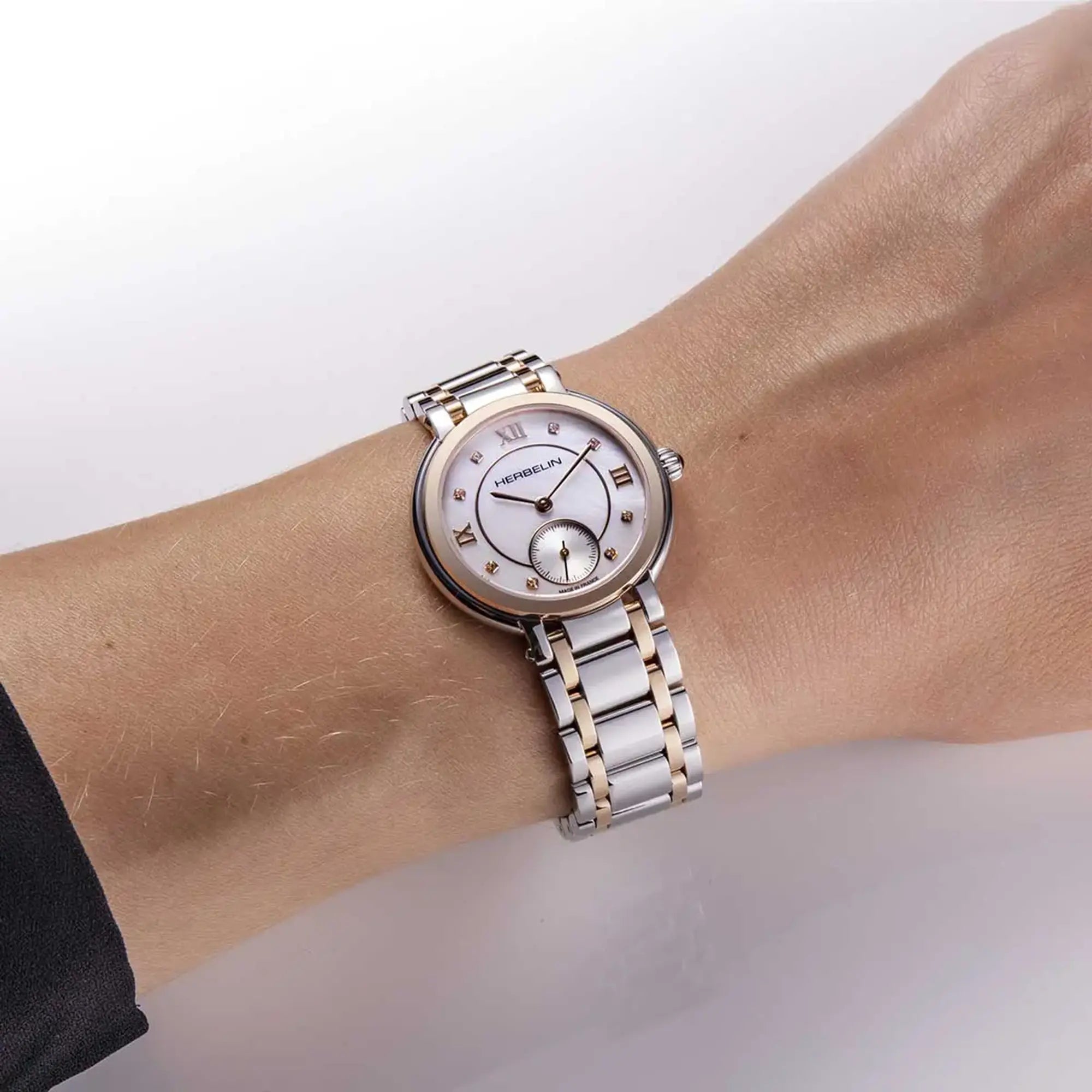 Au poignet féminin, cadran nacre blanche et bracelet acier PVD or rose visibles