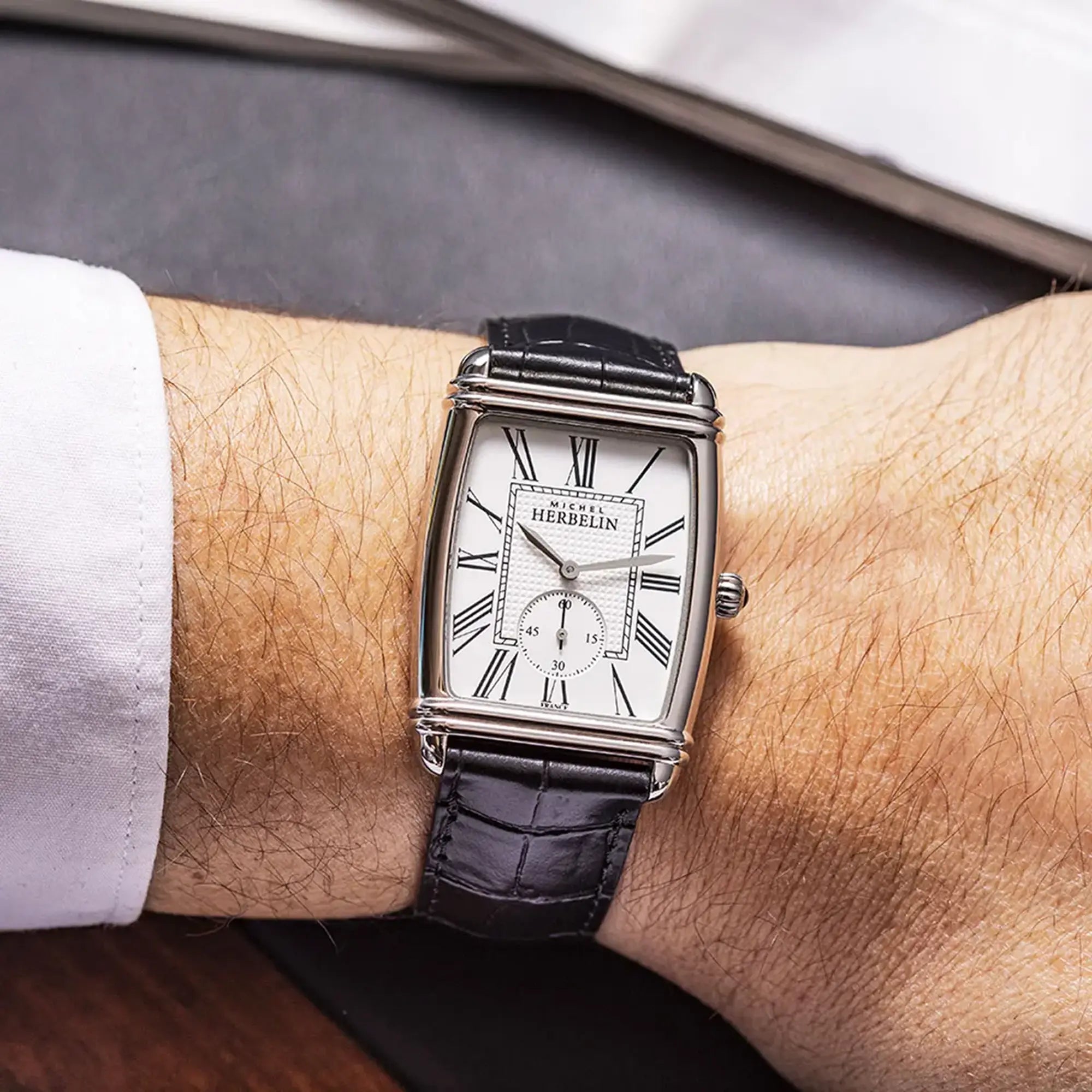 Au poignet masculin, cadran argent blanc et bracelet cuir visibles