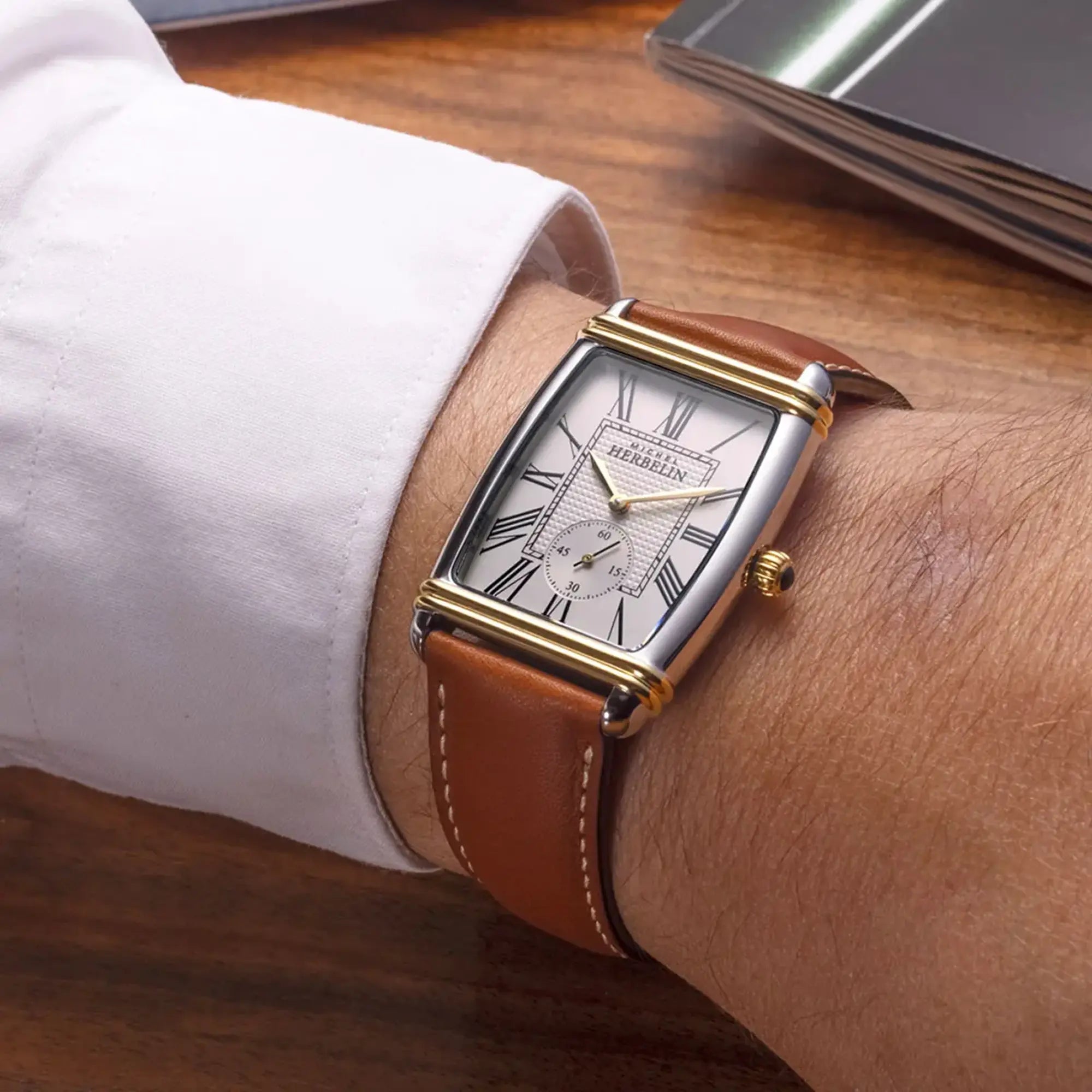 Au poignet masculin, cadran argent guilloché et bracelet cuir visibles