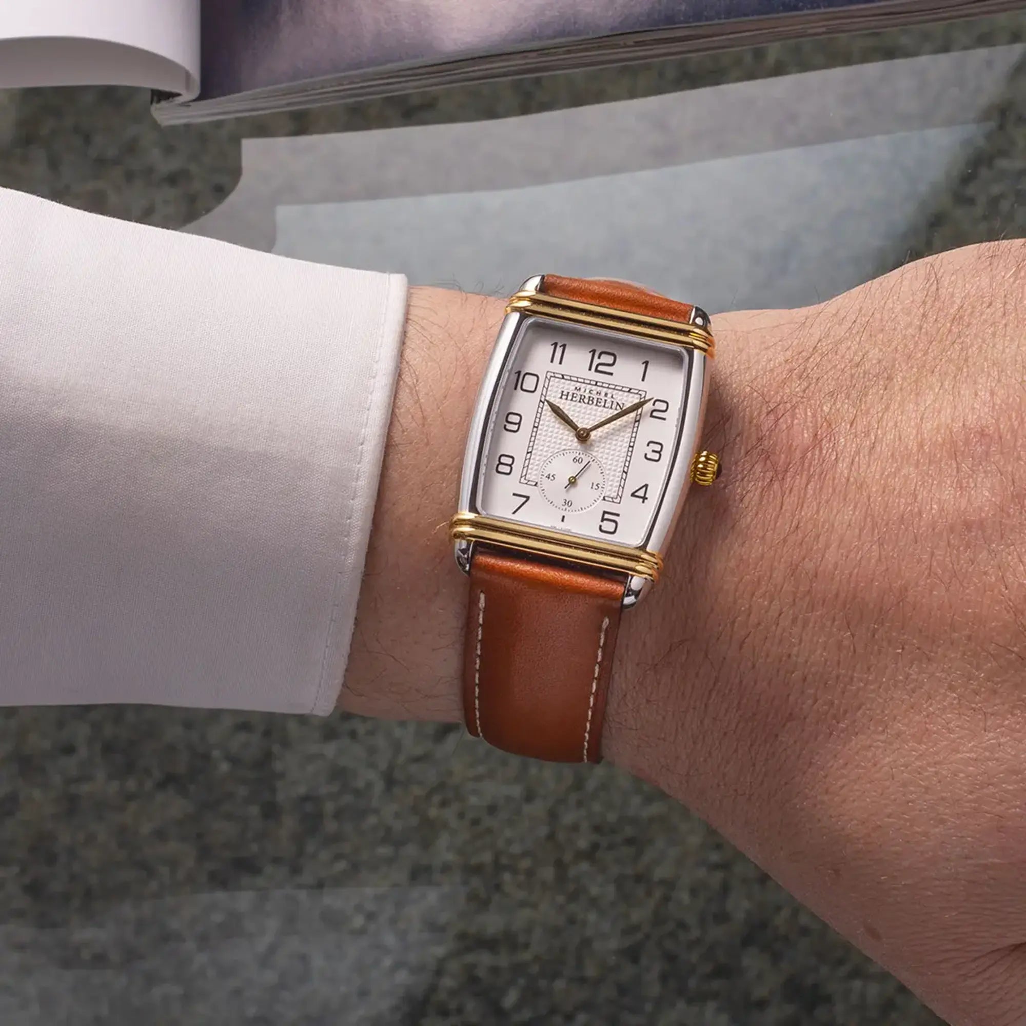 Au poignet masculin, cadran argent guilloché et bracelet cuir visibles