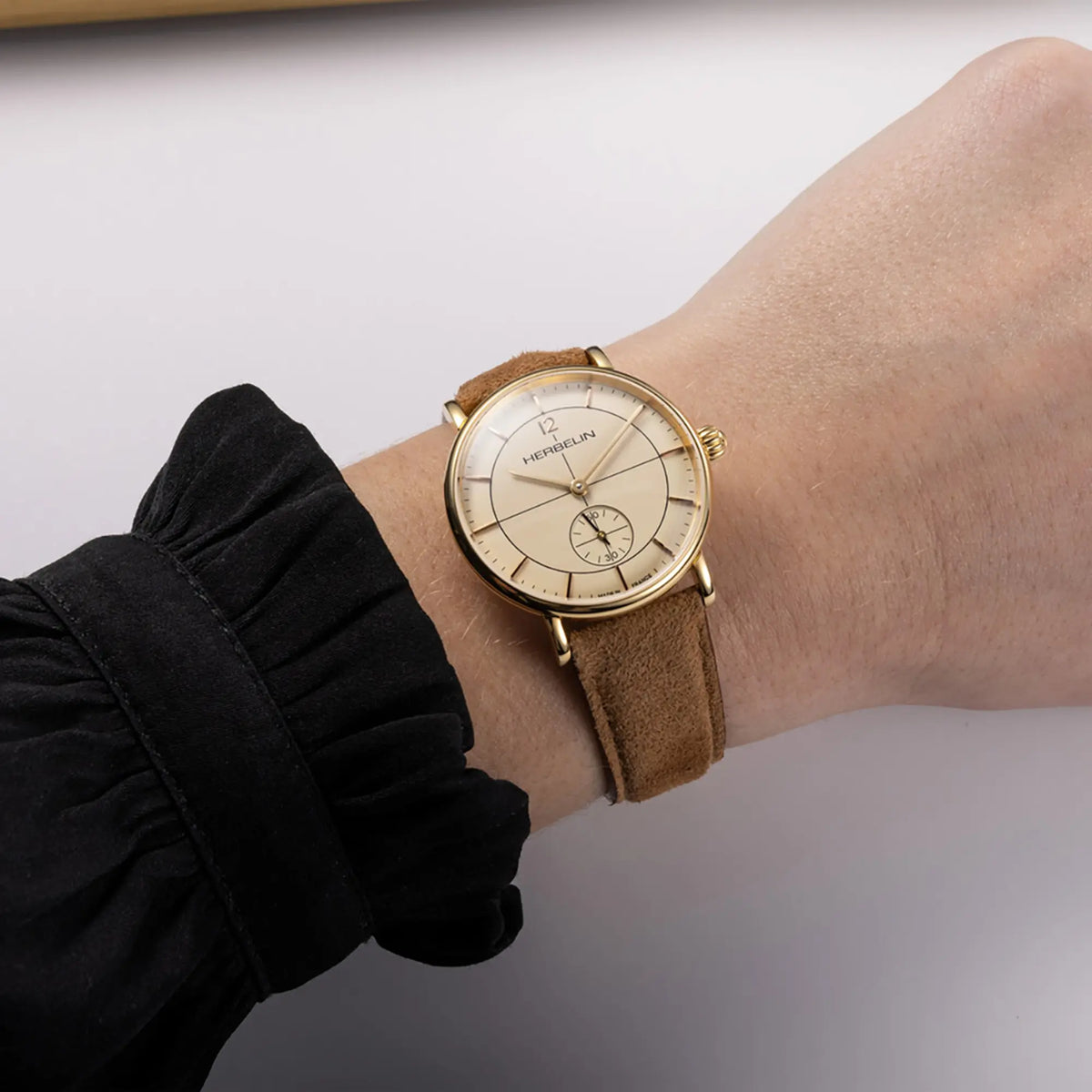⁣⁢En la muñeca femenina, esfera color marfil y brazalete de piel visibles⁤⁣