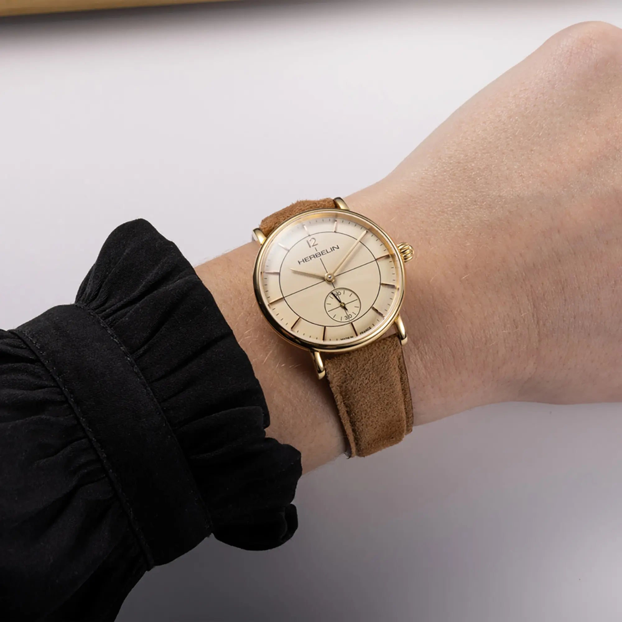 Au poignet féminin, cadran coquille d'œuf et bracelet cuir visibles