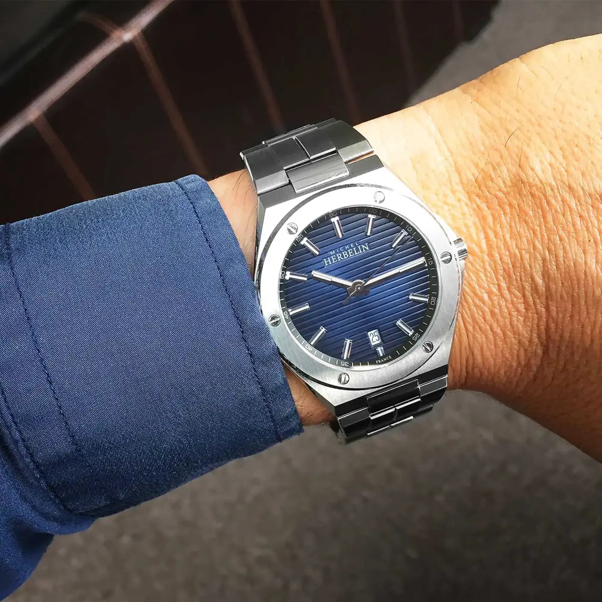 Au poignet masculin, cadran bleu dégradé et bracelet acier visibles