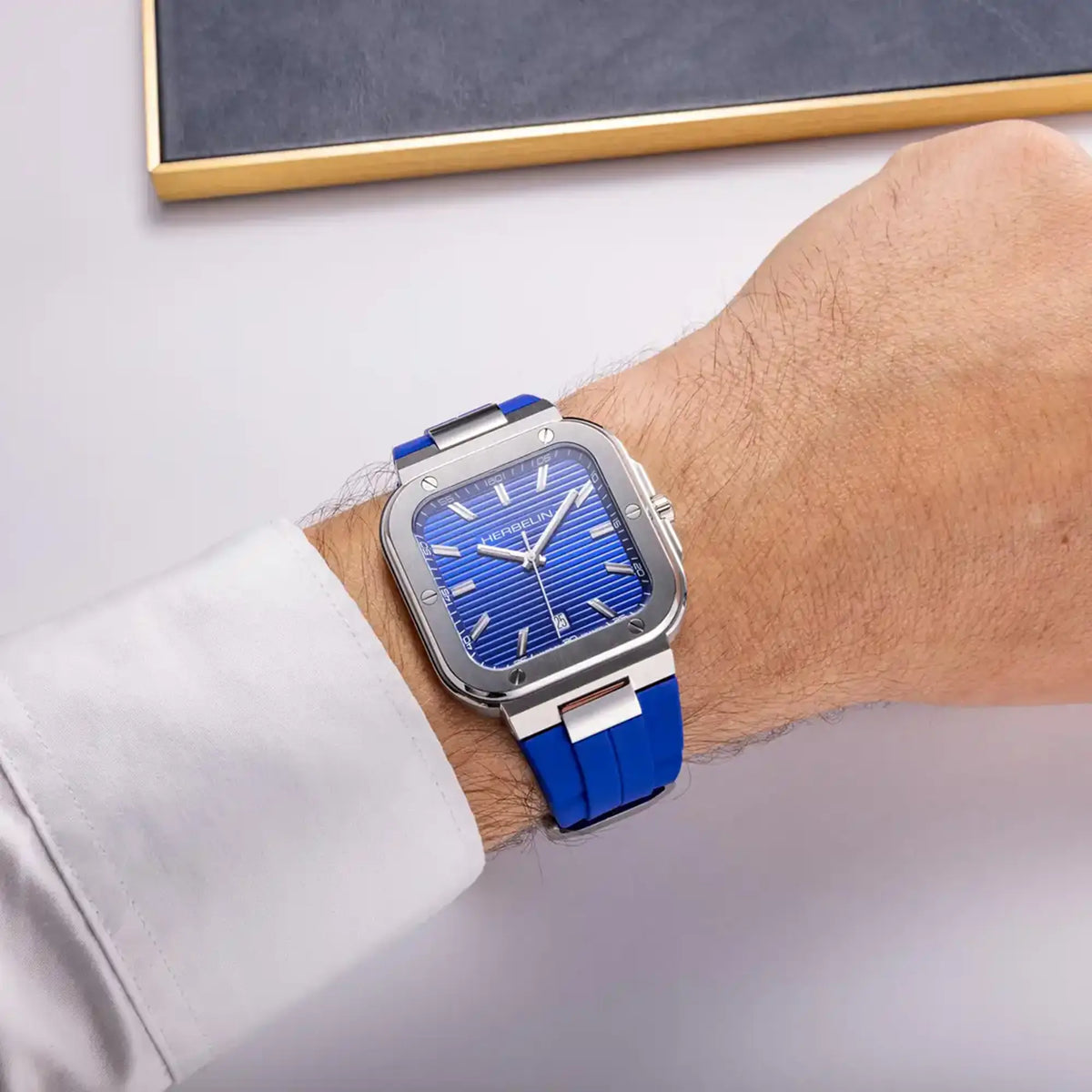 ⁣⁢En muñeca masculina, esfera azul cobalto y brazalete de caucho visibles⁤⁣