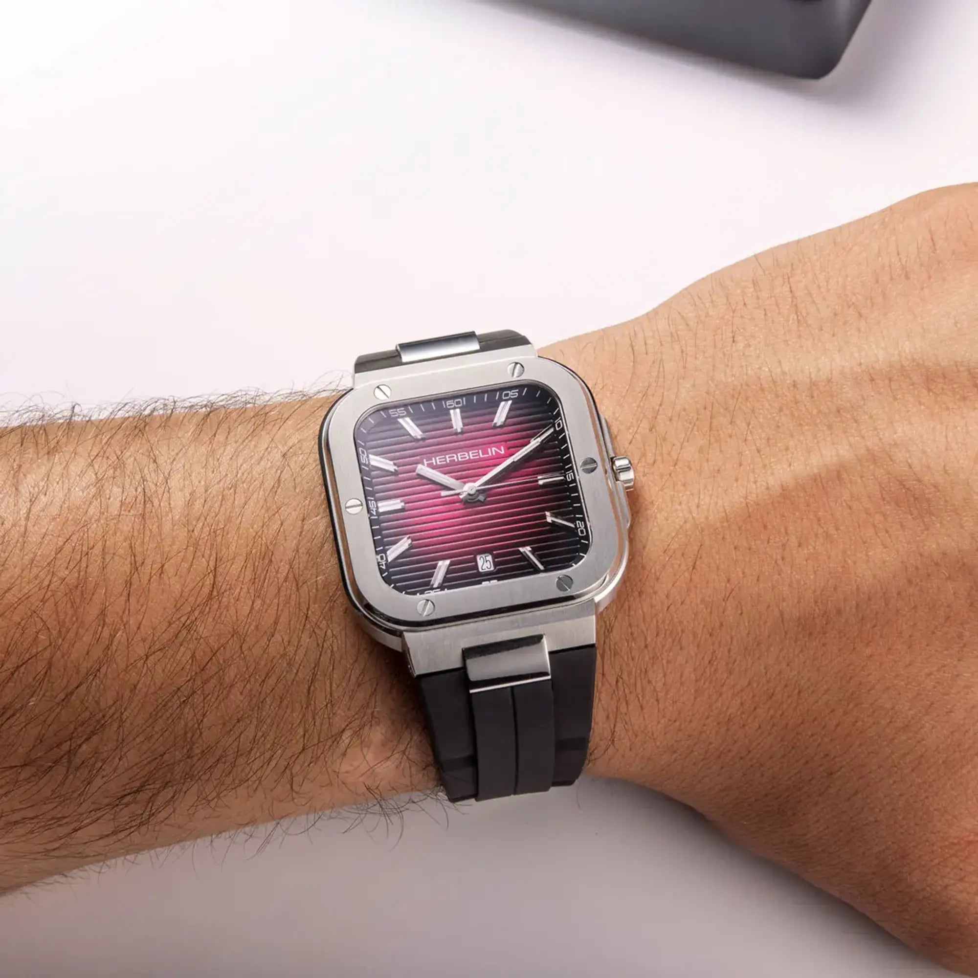 Au poignet masculin, cadran bordeaux dégradé et bracelet caoutchouc visibles