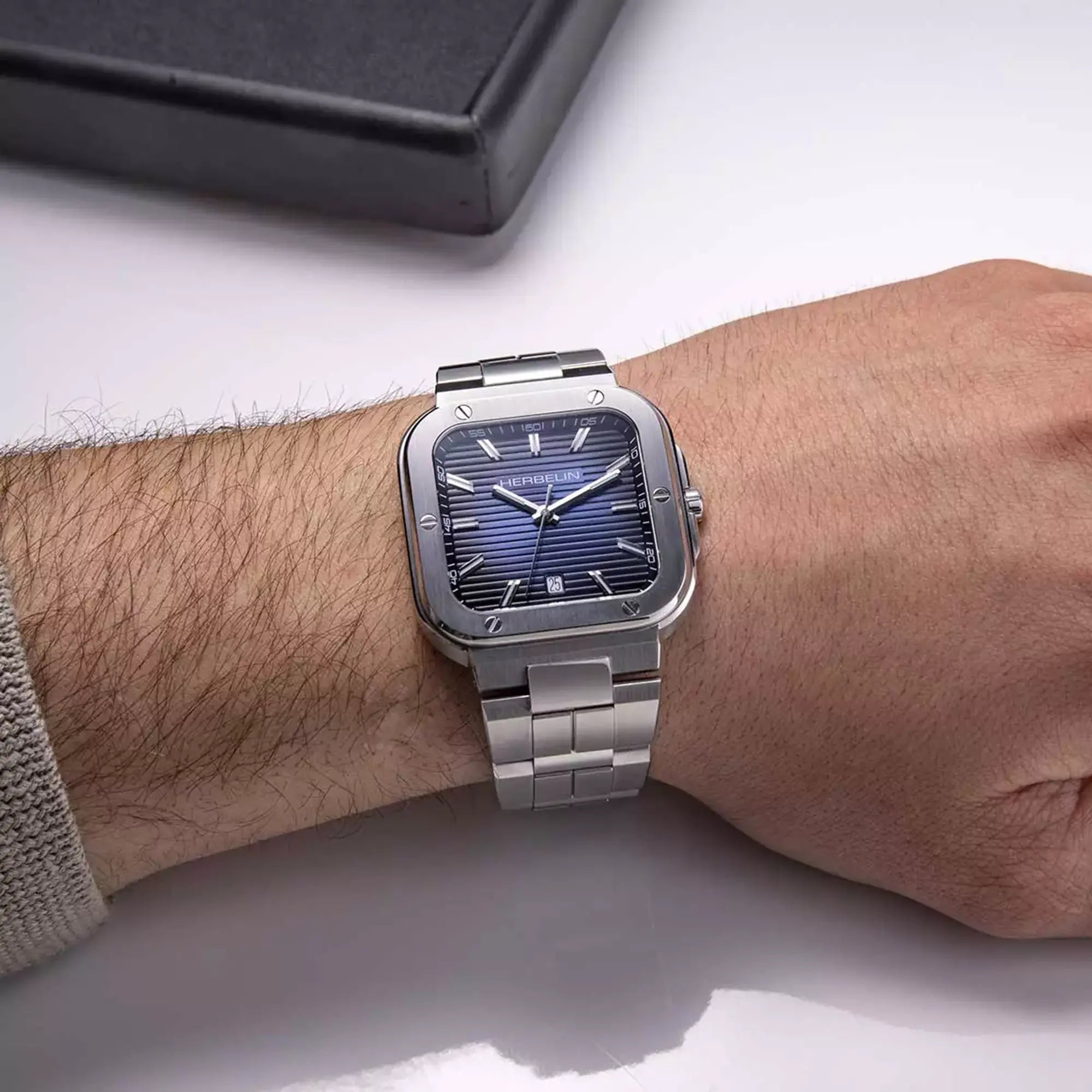 Au poignet masculin, cadran bleu dégradé et bracelet acier visibles