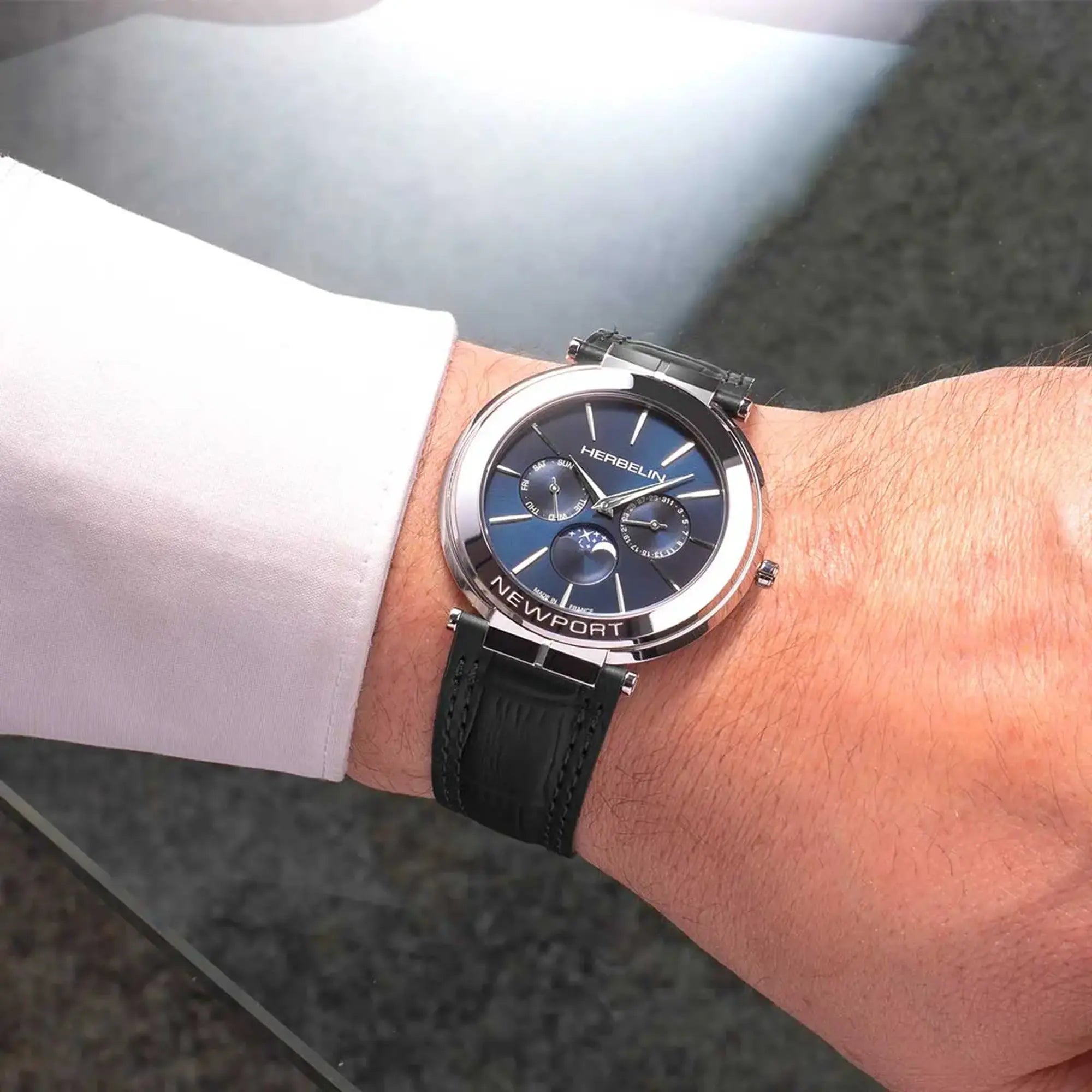 Au poignet masculin, cadran bleu profond et bracelet cuir visibles