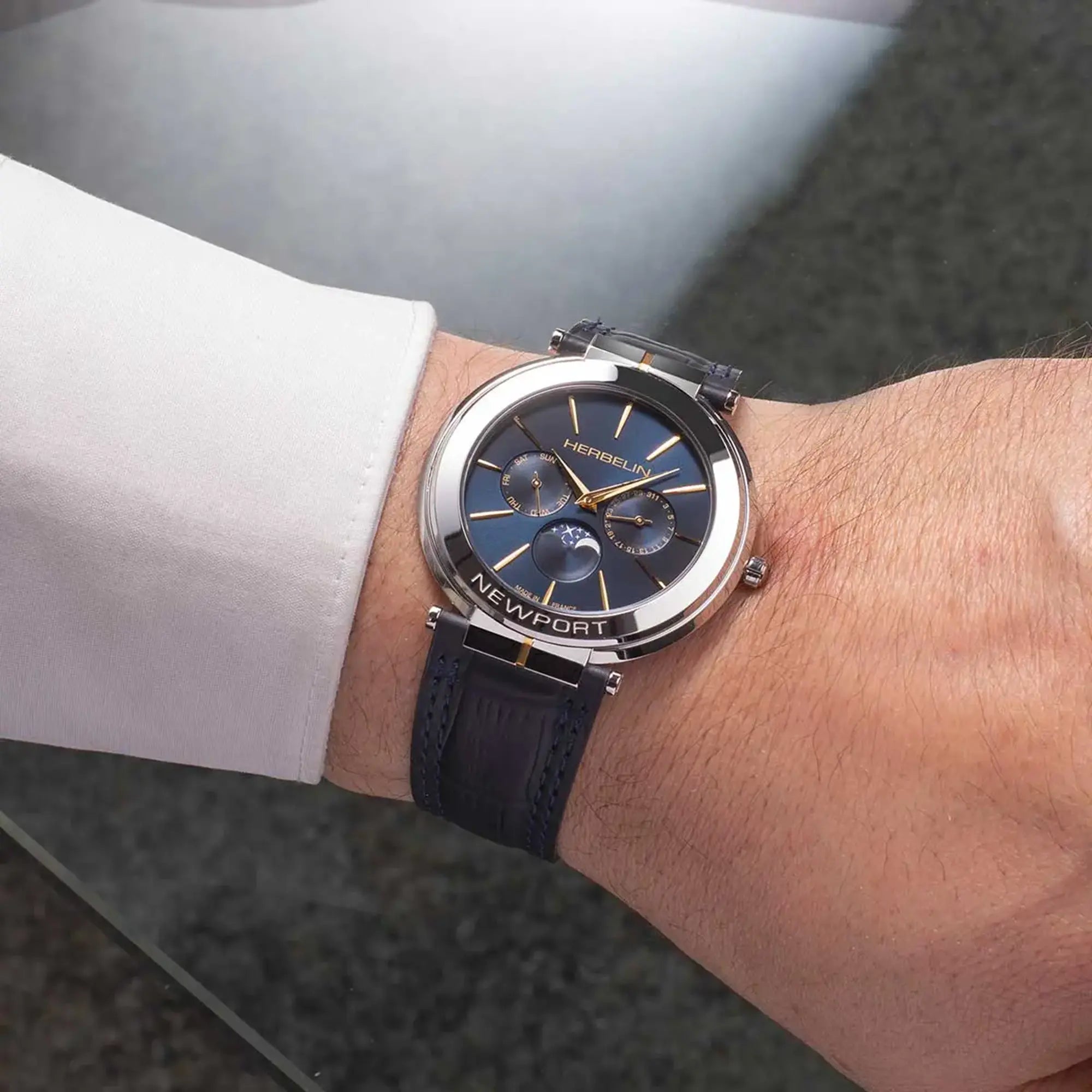 Au poignet masculin, cadran bleu profond et bracelet cuir visibles