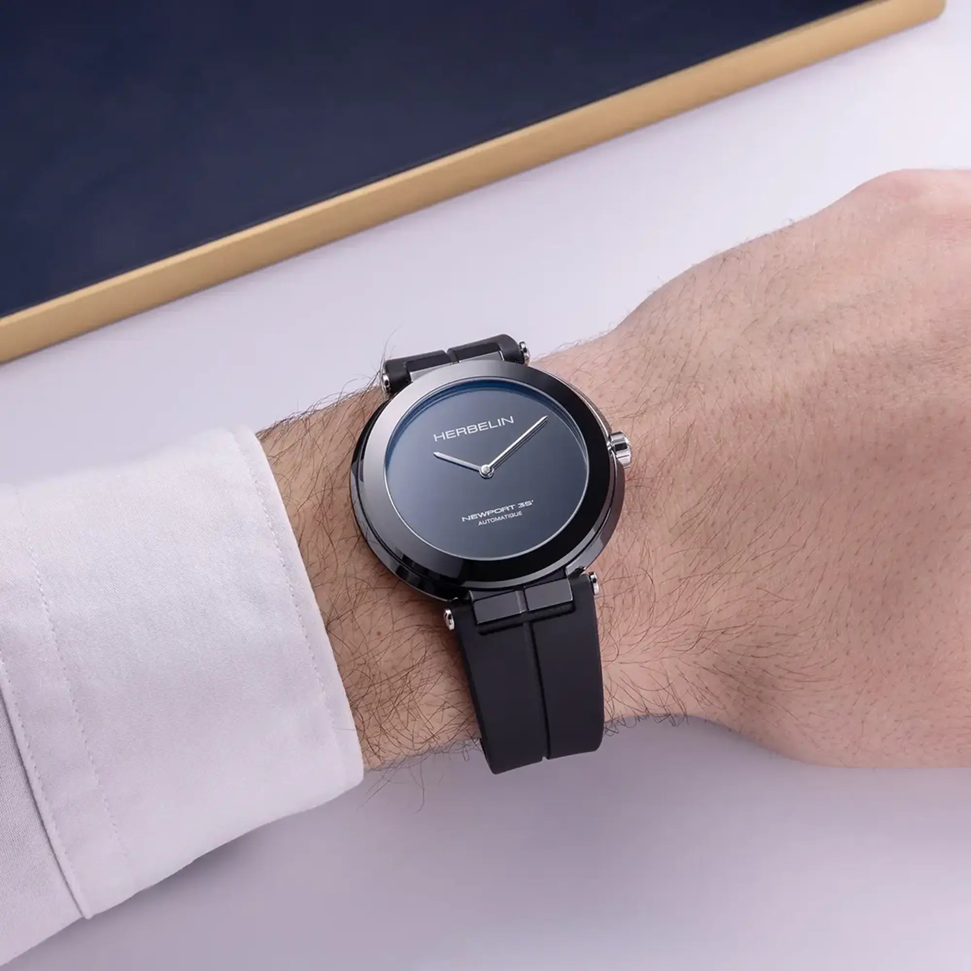 Au poignet masculin, cadran céramique noire polie et bracelet caoutchouc visibles