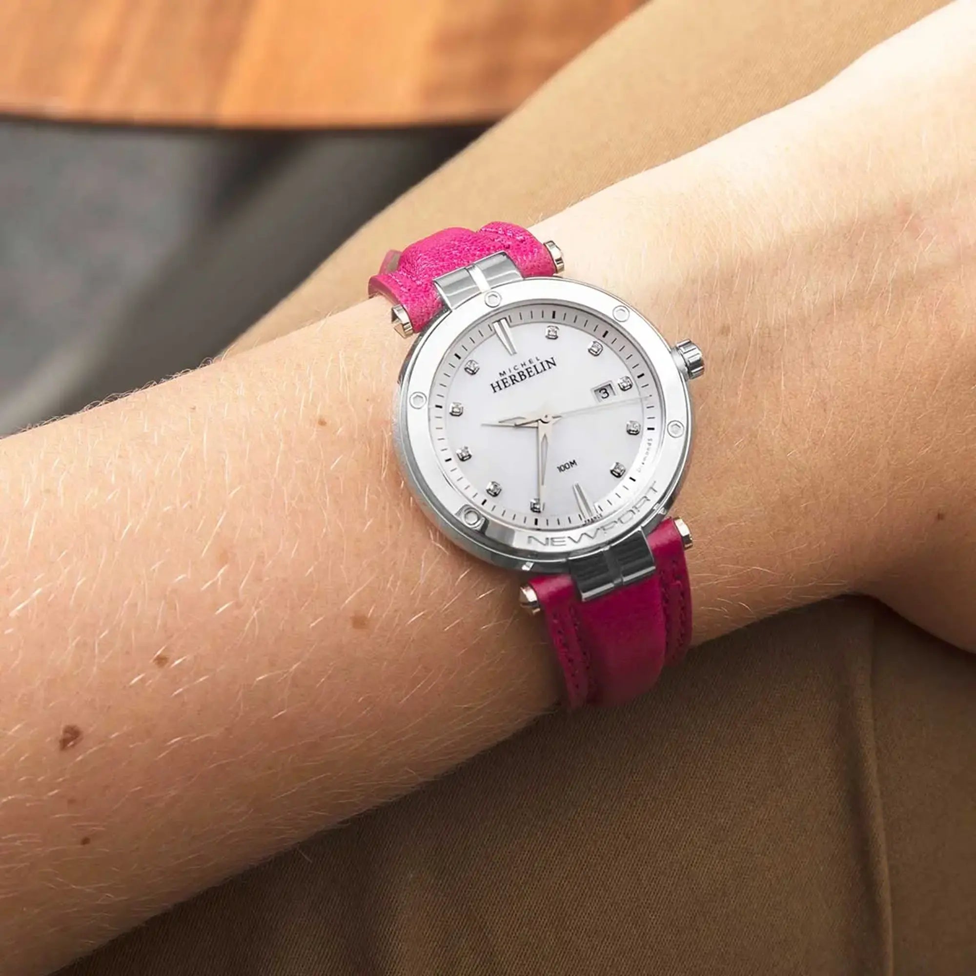 Au poignet féminin, cadran nacre blanche et bracelet cuir visibles