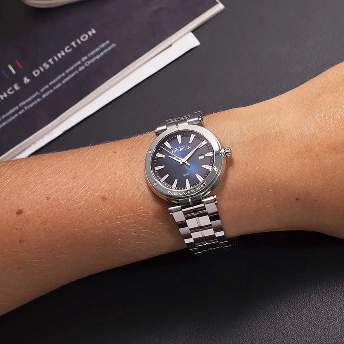 ⁣⁢En la muñeca femenina, esfera azul degradada y brazalete de acero visibles⁤⁣
