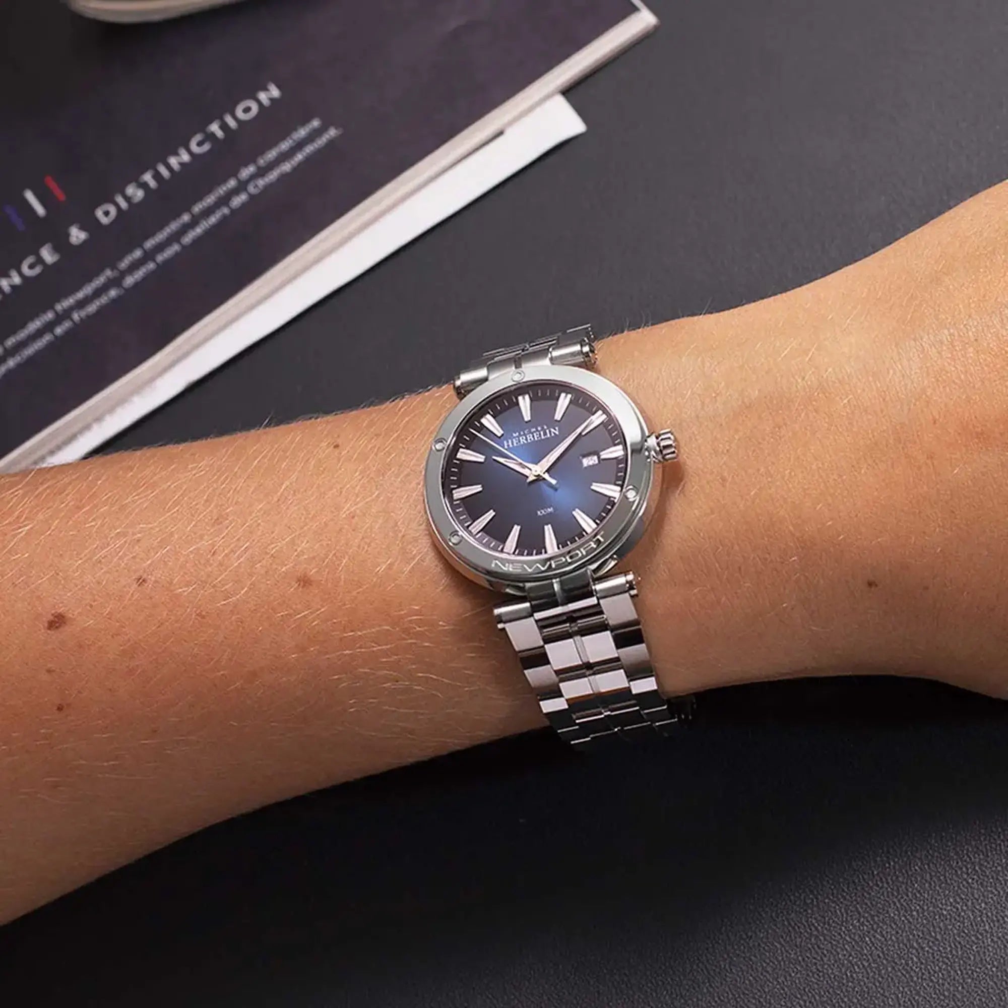 Au poignet féminin, cadran bleu dégradé et bracelet acier visibles