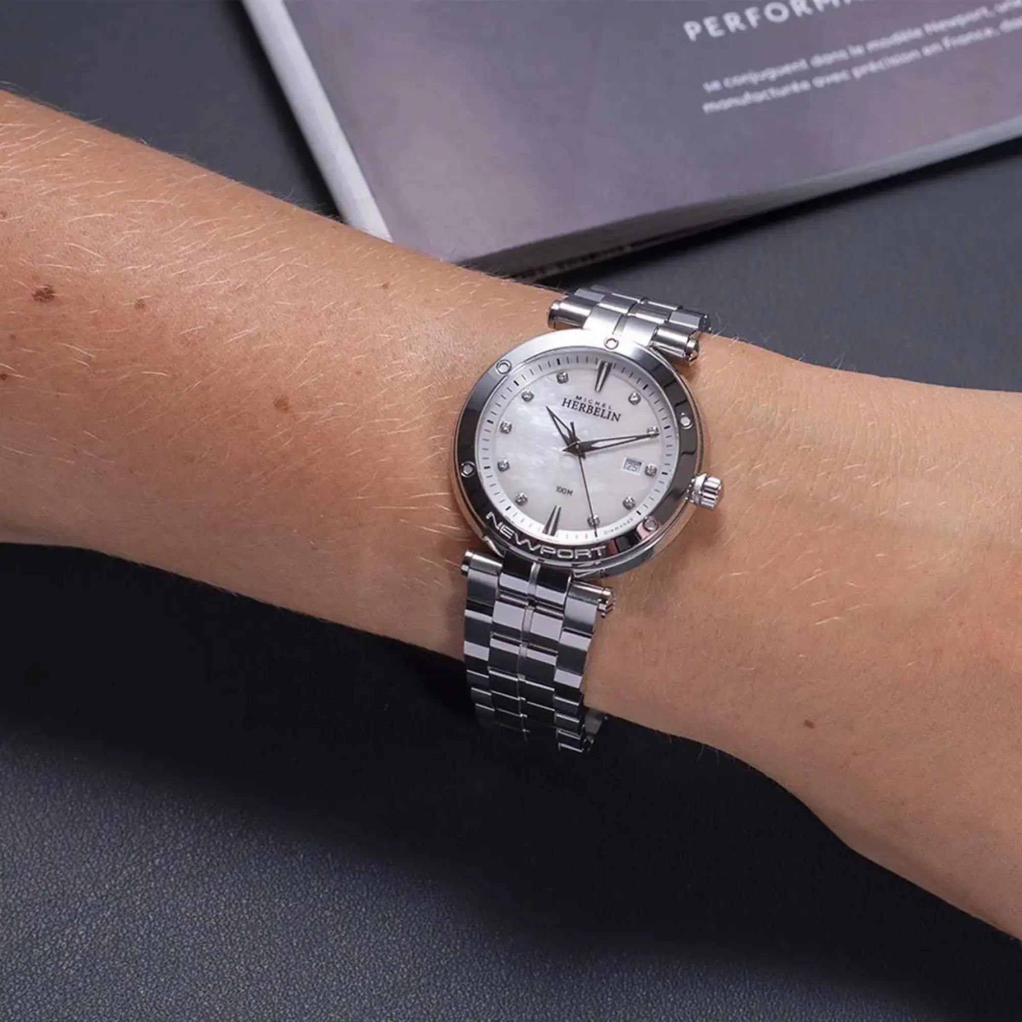 Au poignet féminin, cadran nacre blanche et bracelet acier visibles