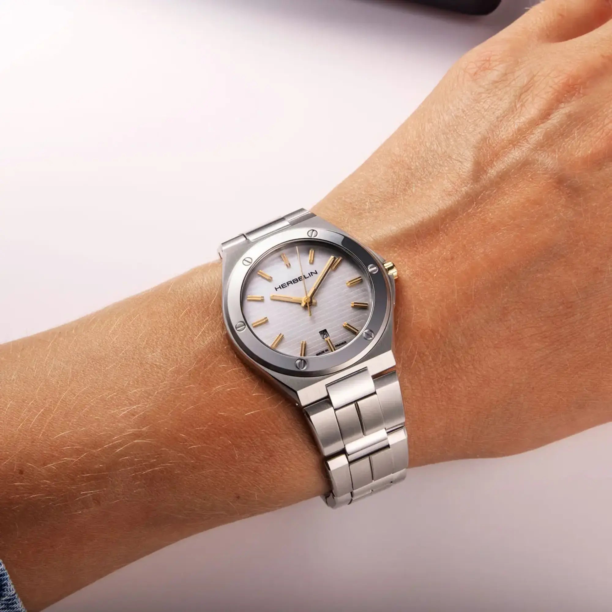 Au poignet féminin, cadran nacre blanche et bracelet acier visibles