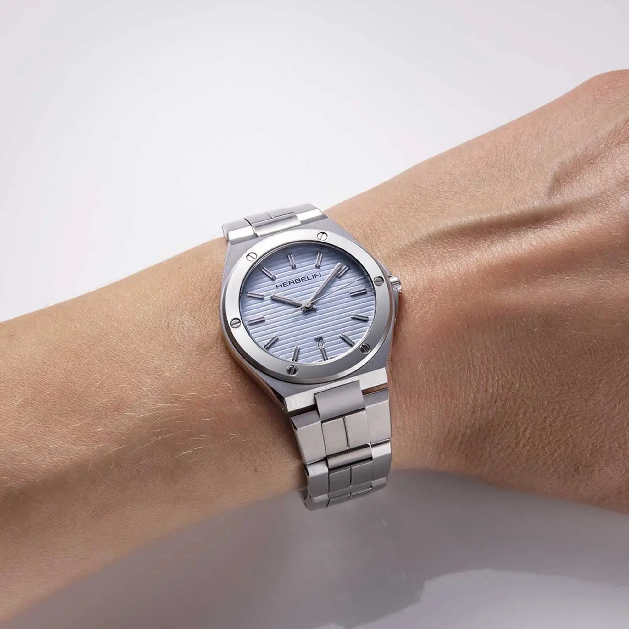 Au poignet féminin, cadran bleu arctique et bracelet acier visibles