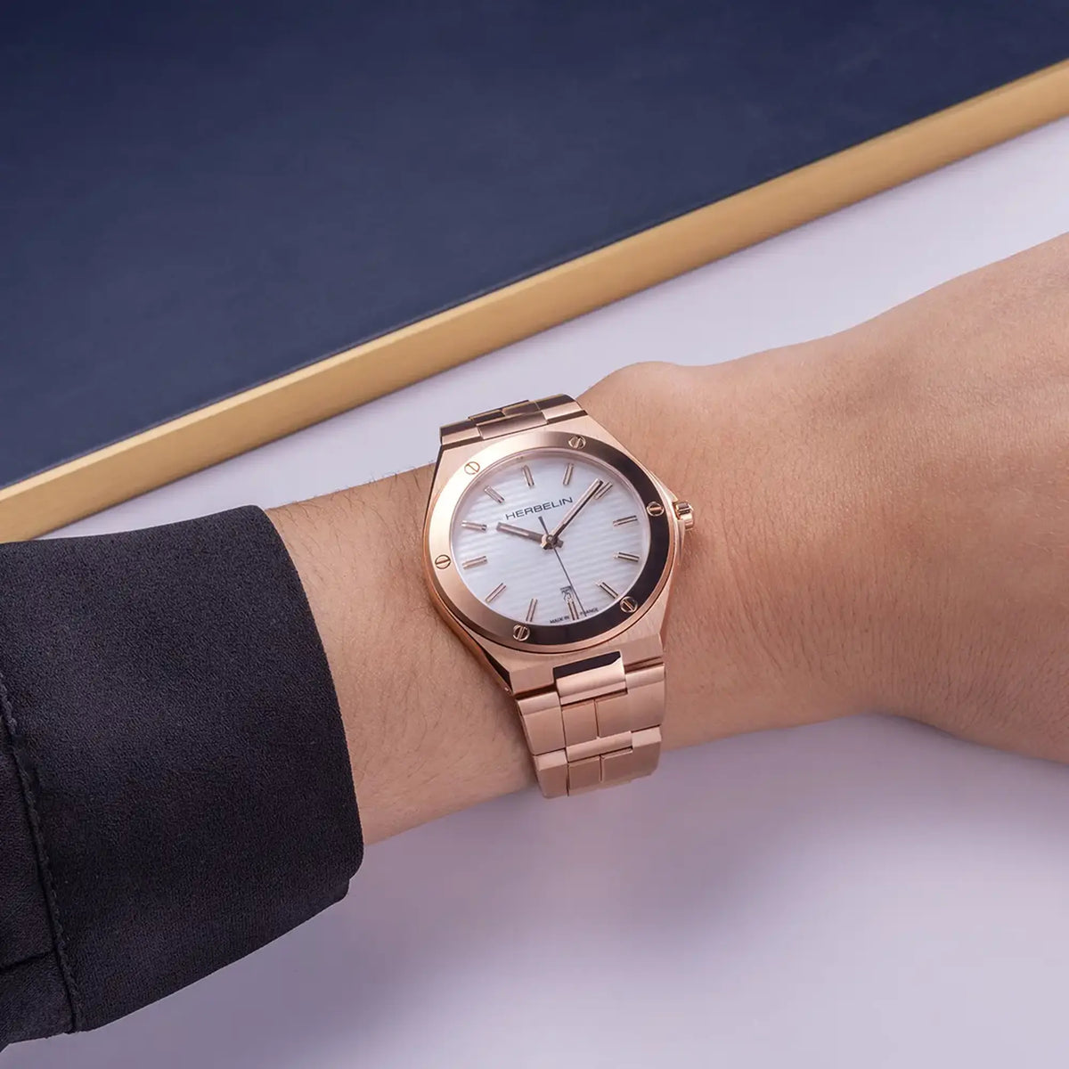 ⁣⁢En la muñeca femenina, esfera nácar blanco y brazalete de acero PVD oro rosa visibles⁤⁣