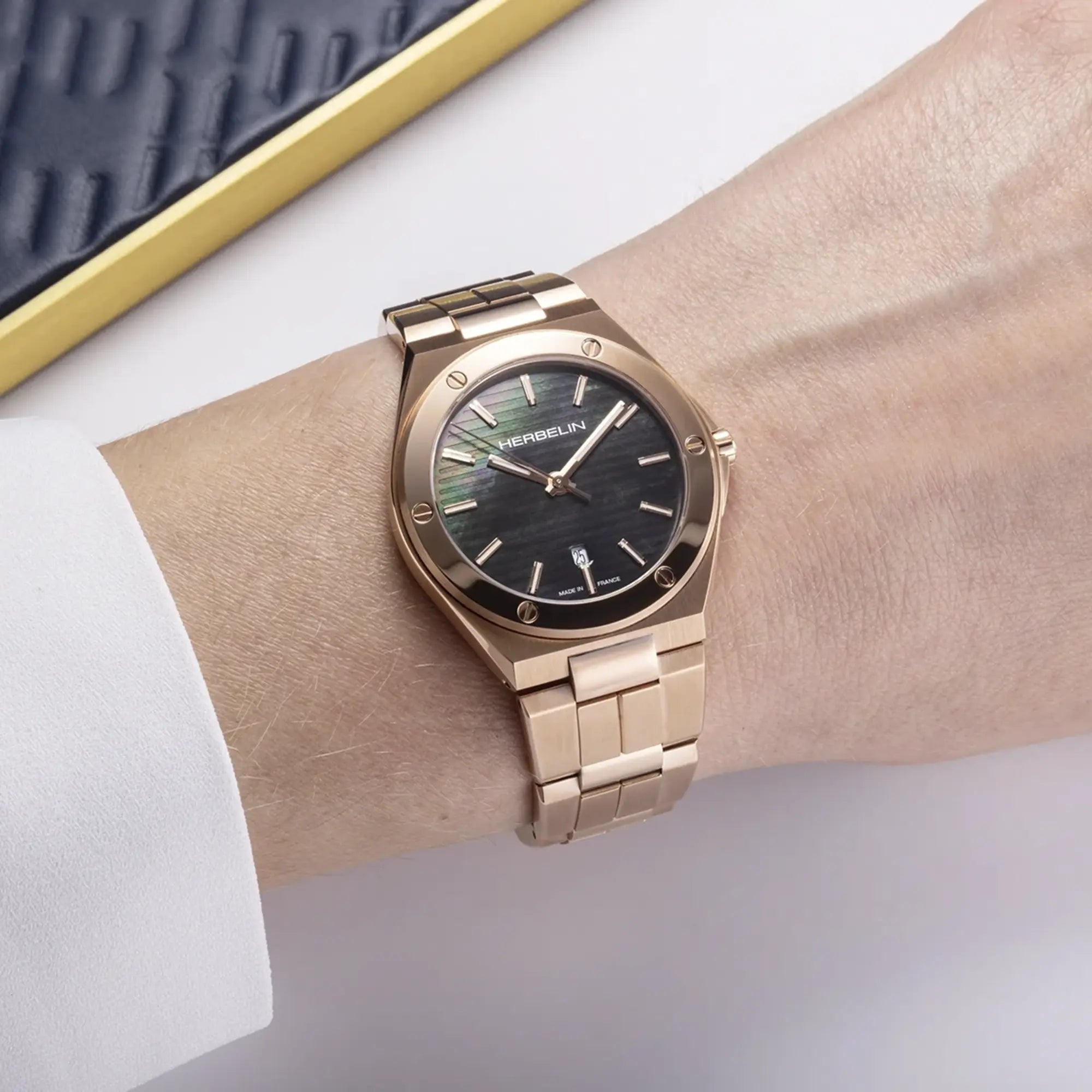 Au poignet féminin, cadran noir et bracelet acier PVD or rose visibles
