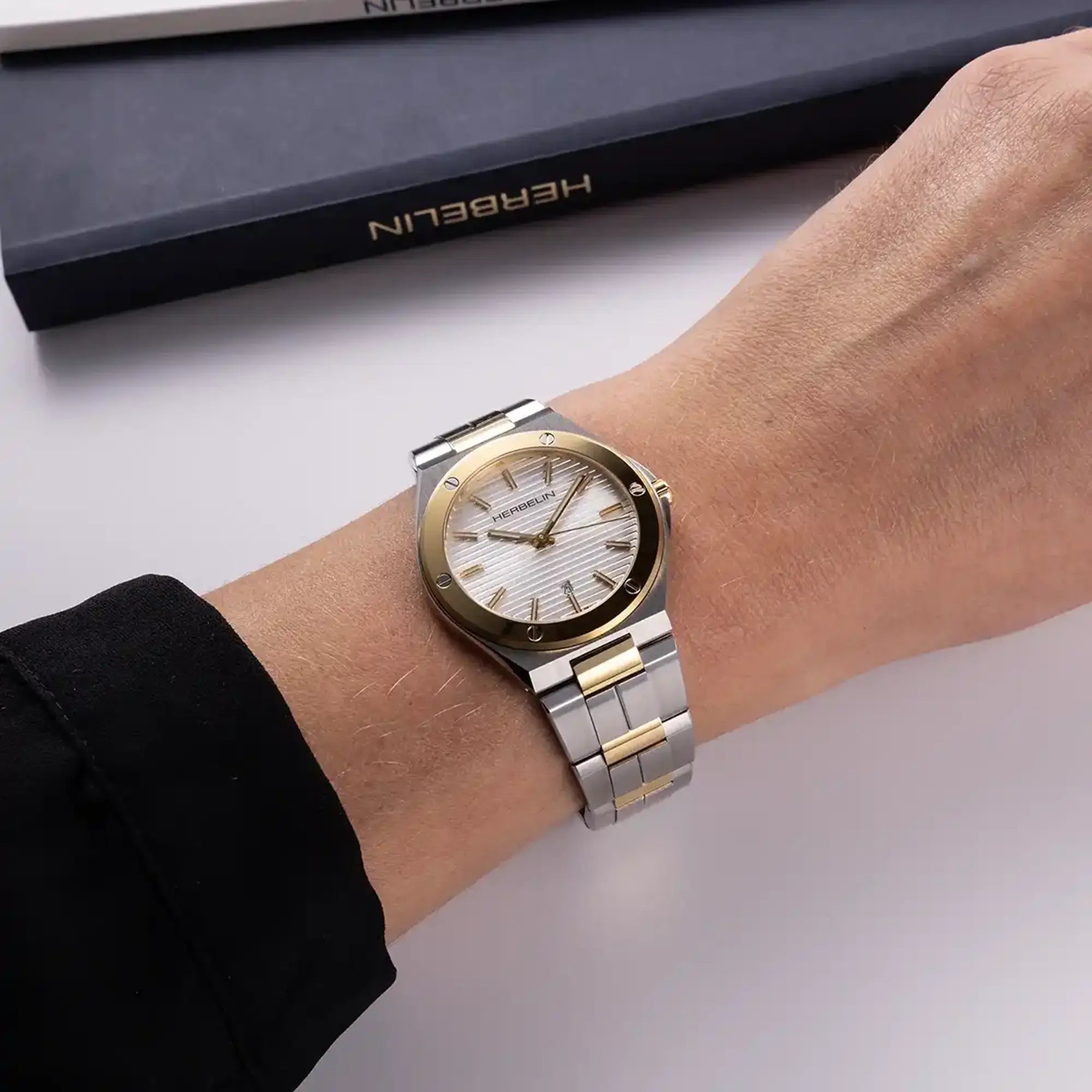 Au poignet féminin, cadran argent blanc et bracelet acier PVD or rose visibles