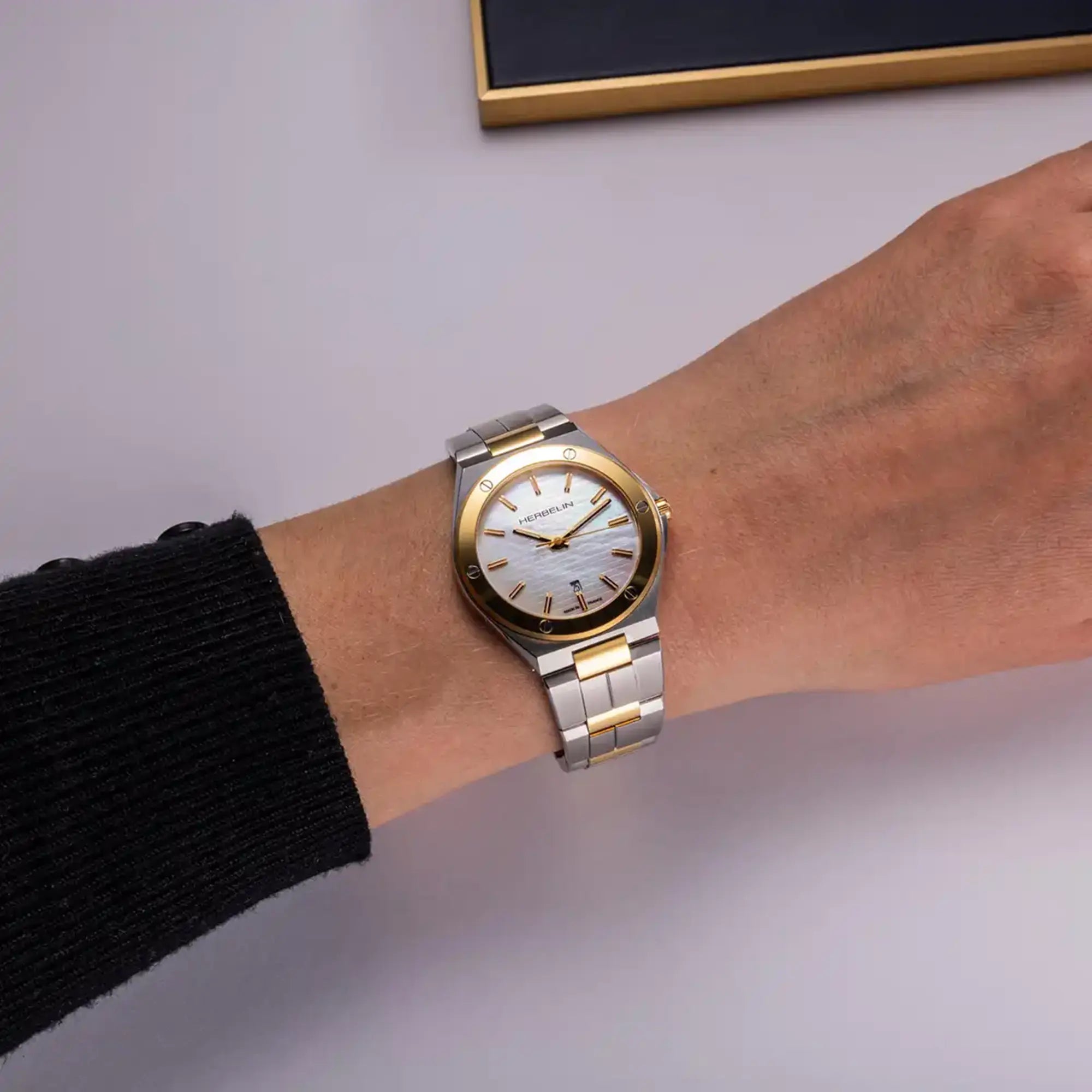 Au poignet féminin, cadran nacre blanche et bracelet acier bicolore visibles