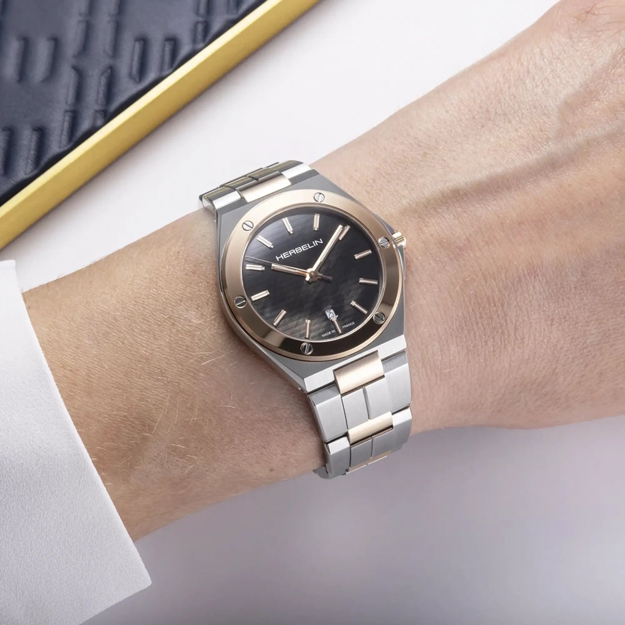 Au poignet féminin, cadran noir et bracelet acier PVD or rose visibles