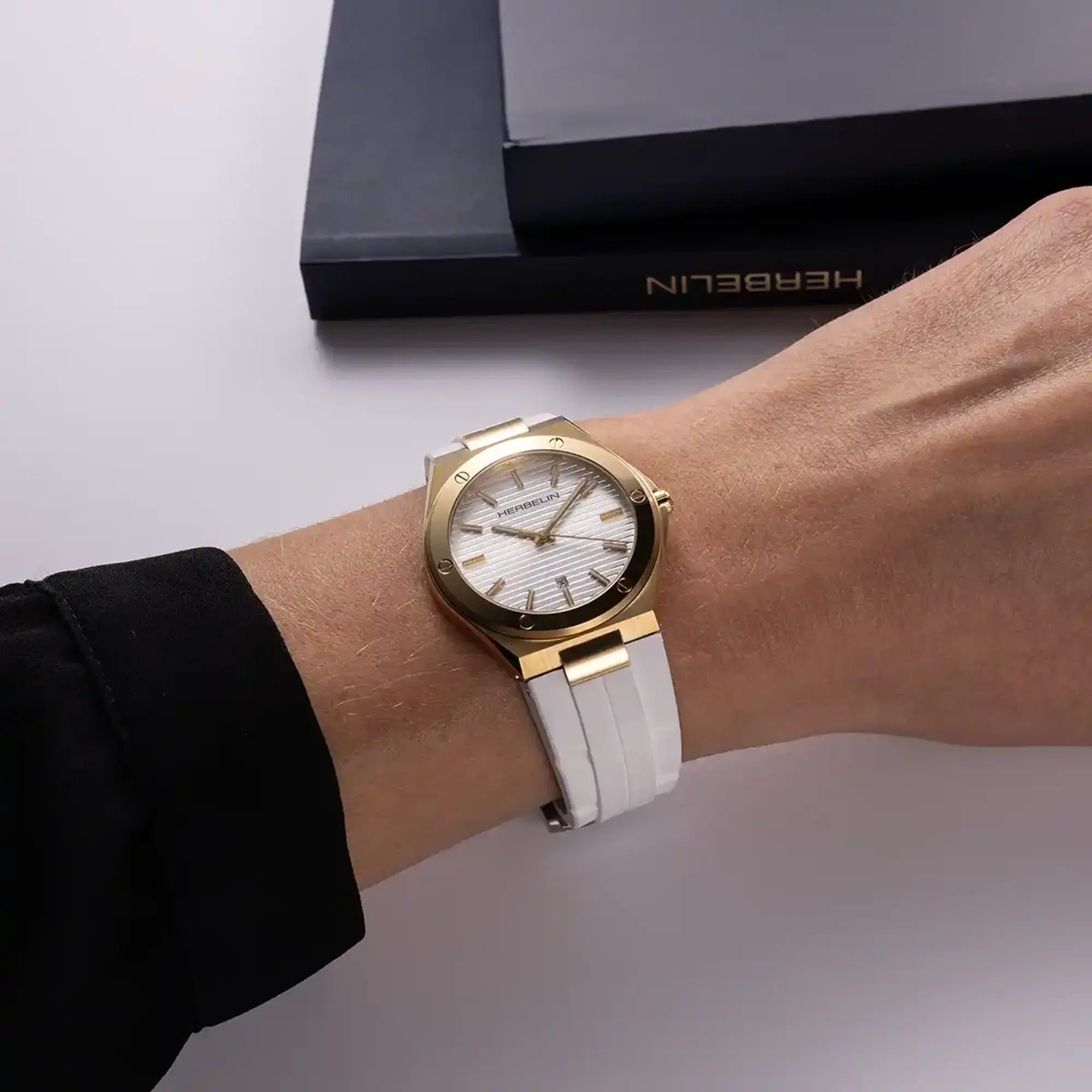 Au poignet féminin, cadran argent blanc et bracelet caoutchouc visibles