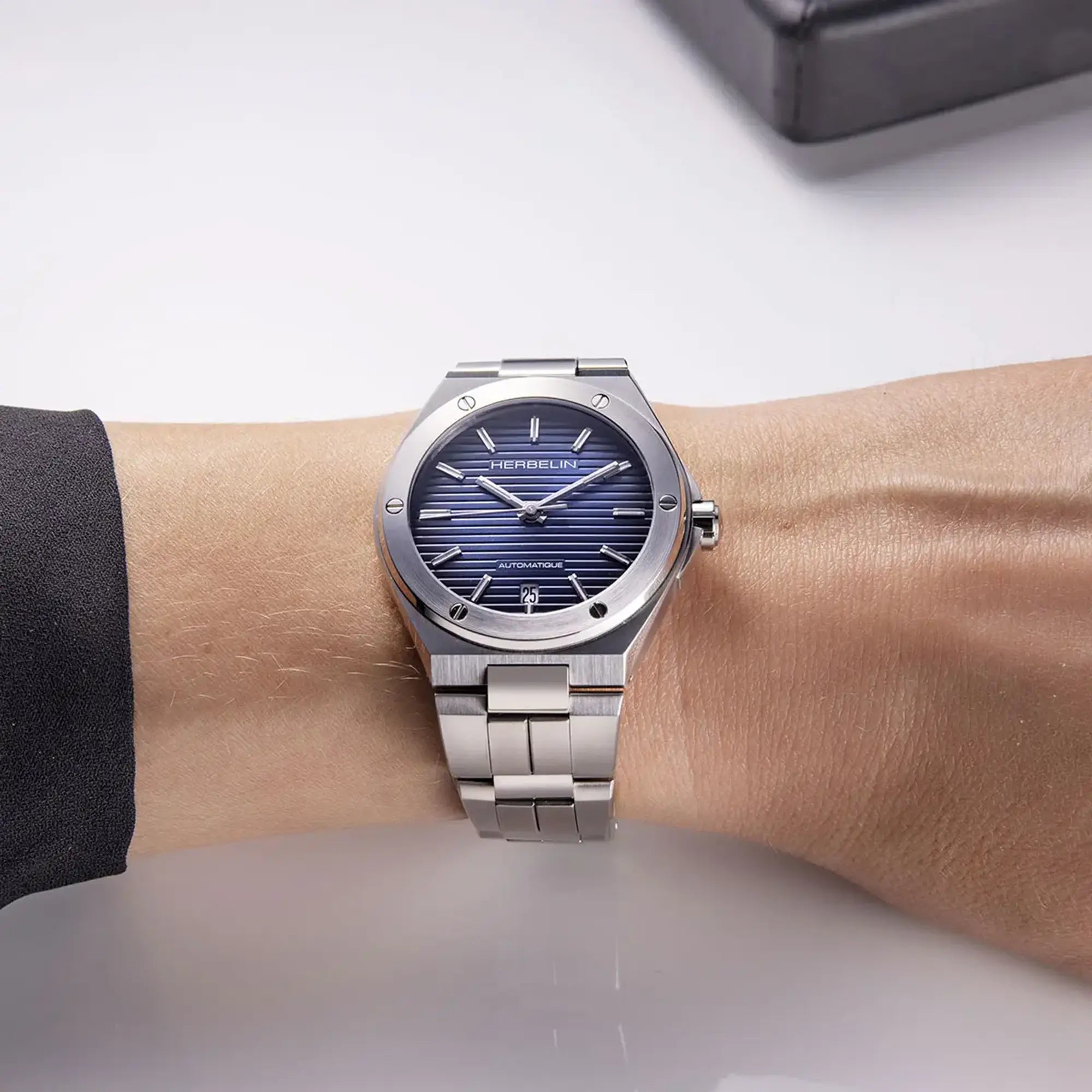 Au poignet féminin, cadran bleu dégradé et bracelet acier visibles
