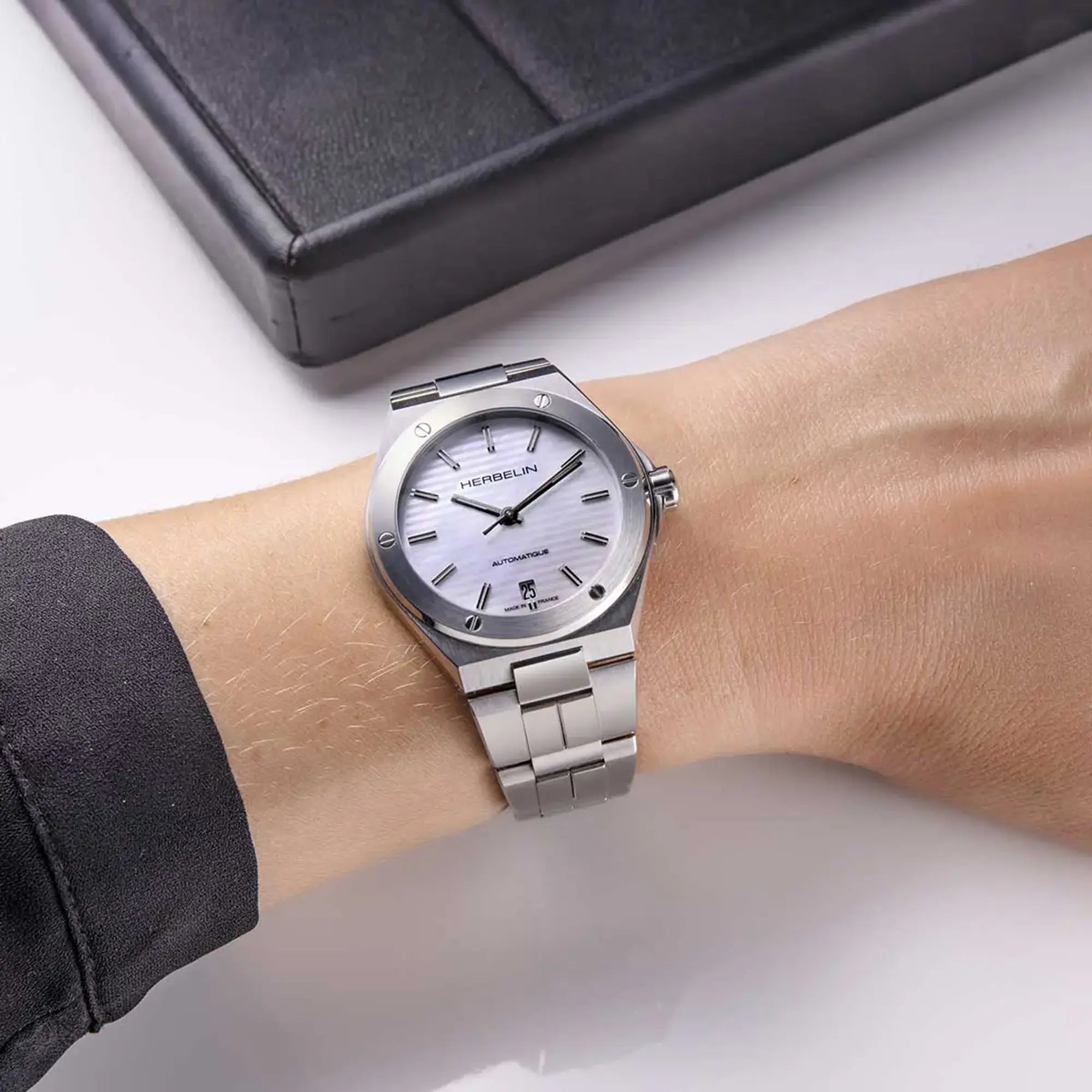 Au poignet féminin, cadran nacre blanche et bracelet acier visibles