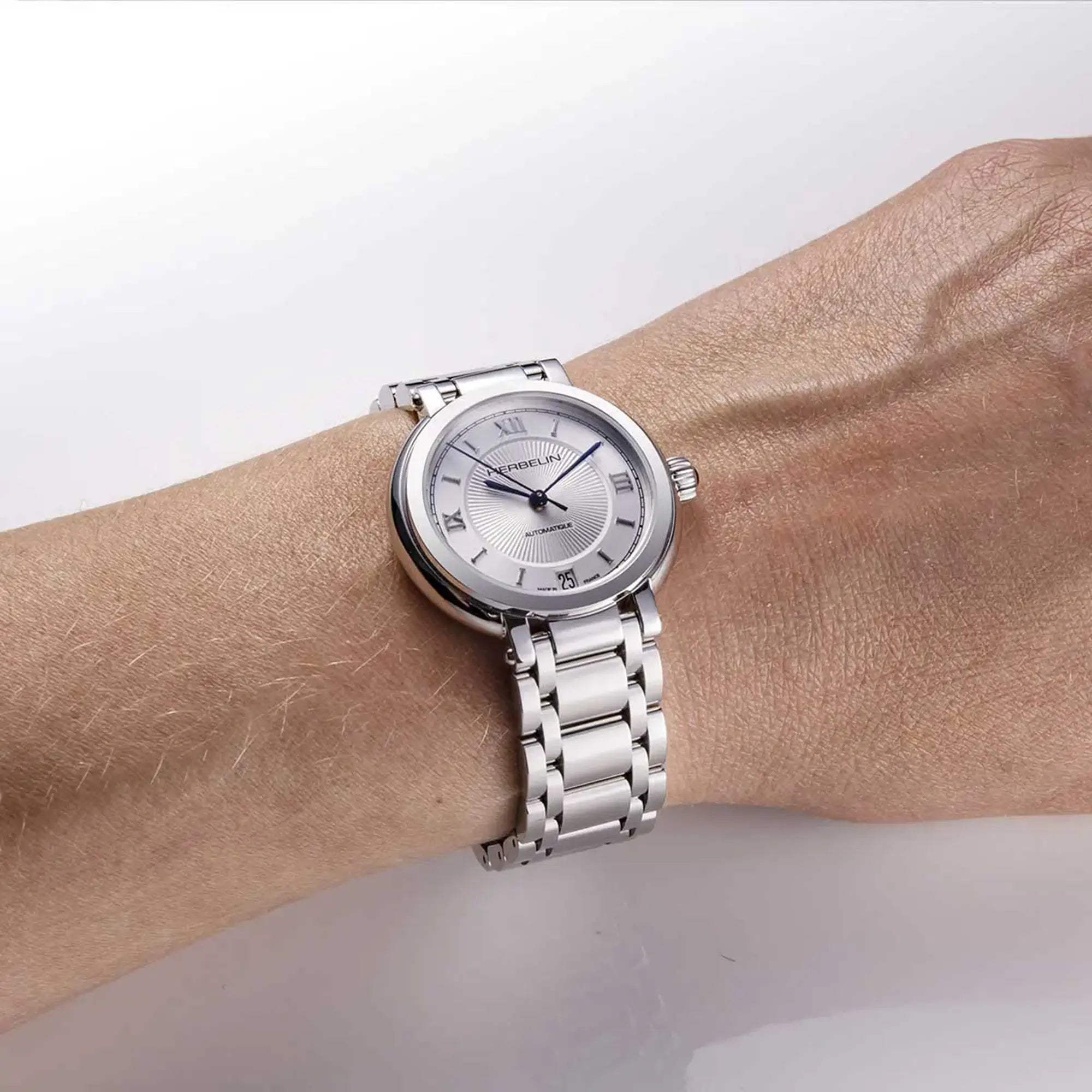 Au poignet féminin, cadran argent guilloché et bracelet acier visibles
