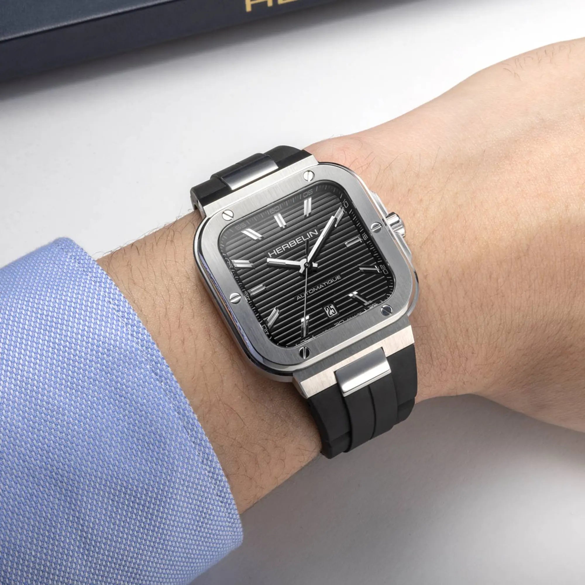Au poignet masculin, cadran noir et bracelet caoutchouc visibles