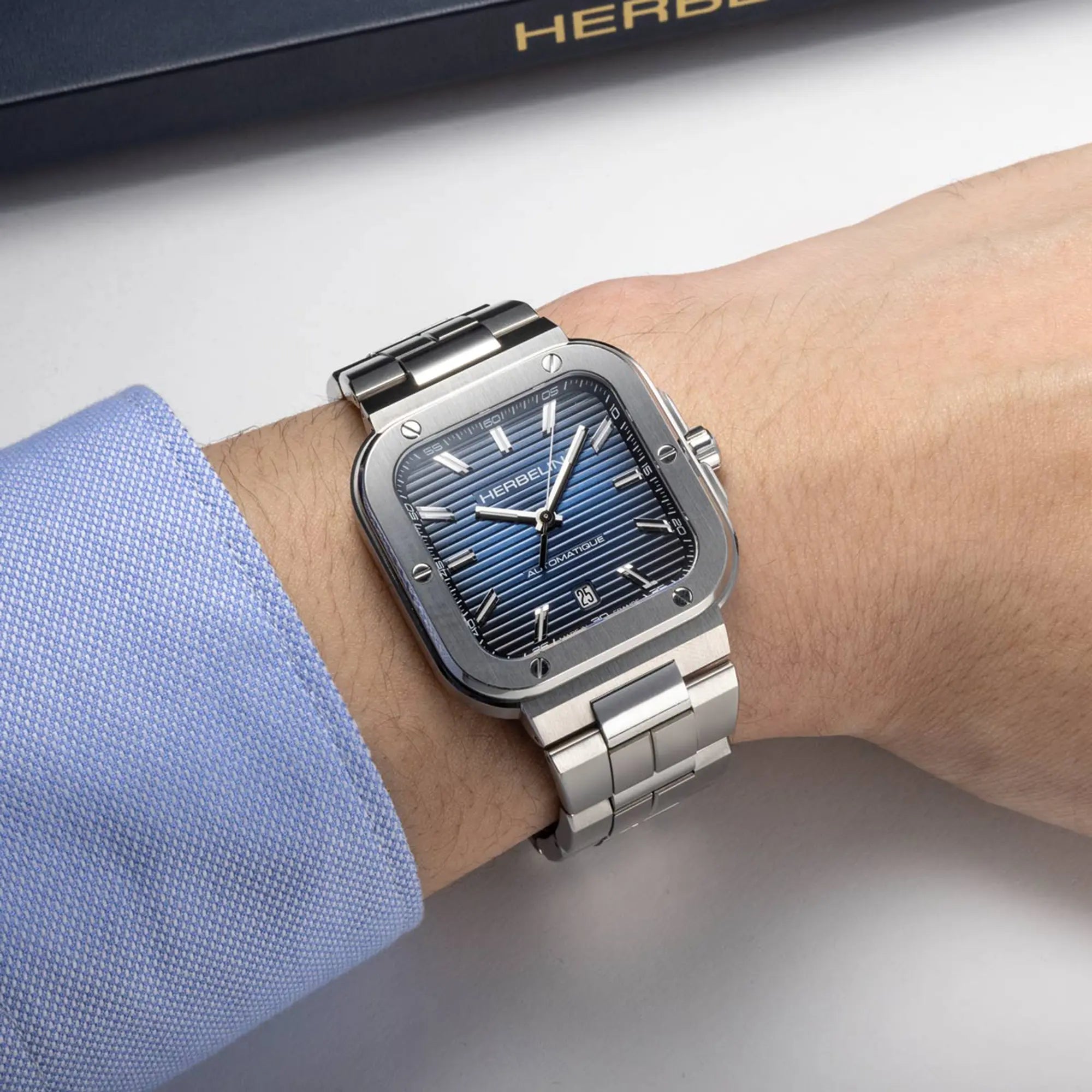Au poignet masculin, cadran bleu dégradé et bracelet acier visibles