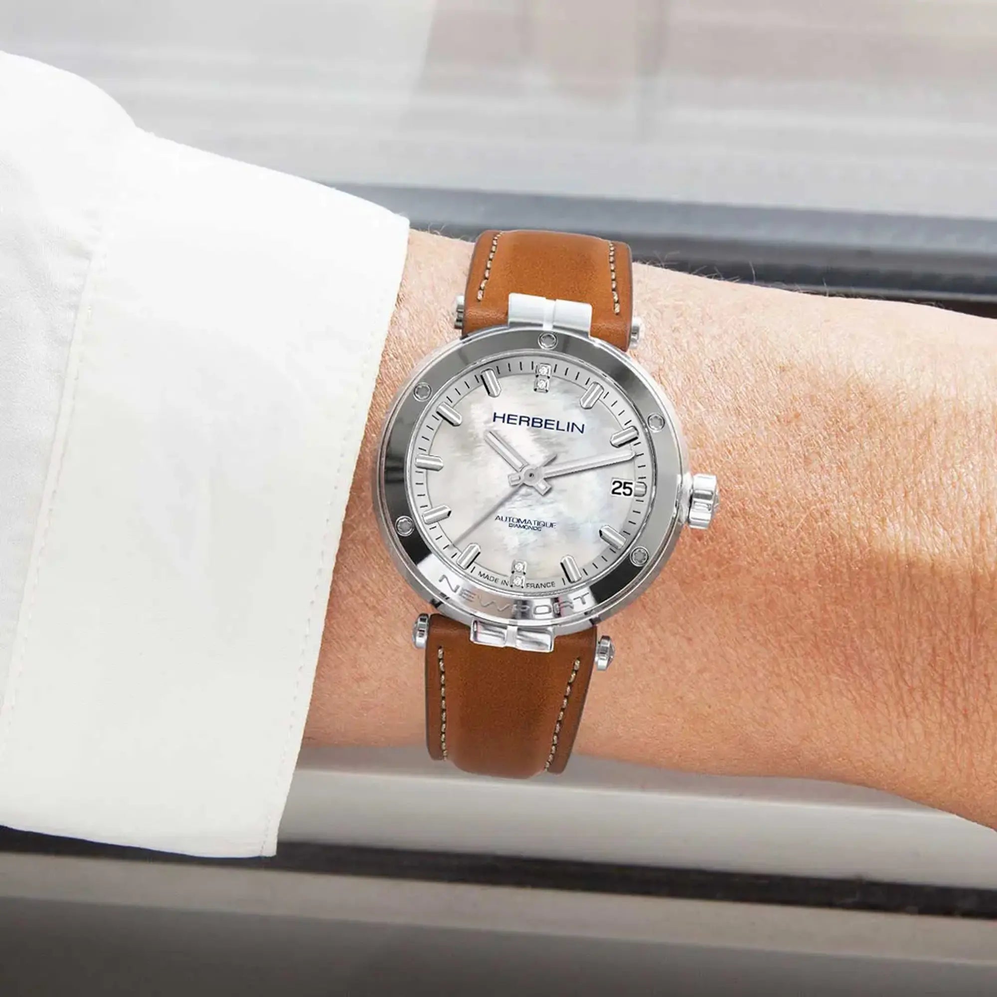 Au poignet féminin, cadran nacre blanche et bracelet cuir visibles
