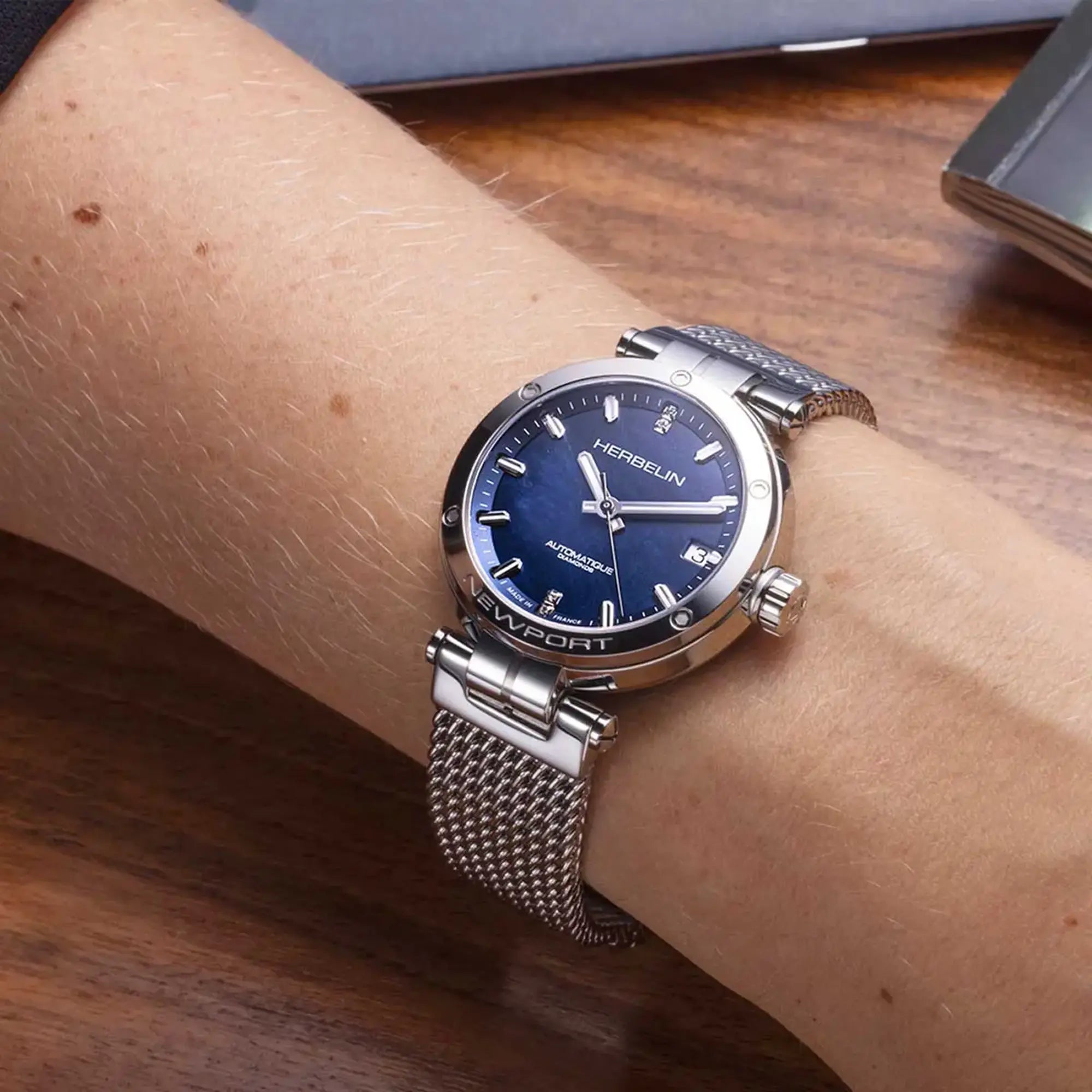 Au poignet féminin, cadran nacre bleue et bracelet acier visibles