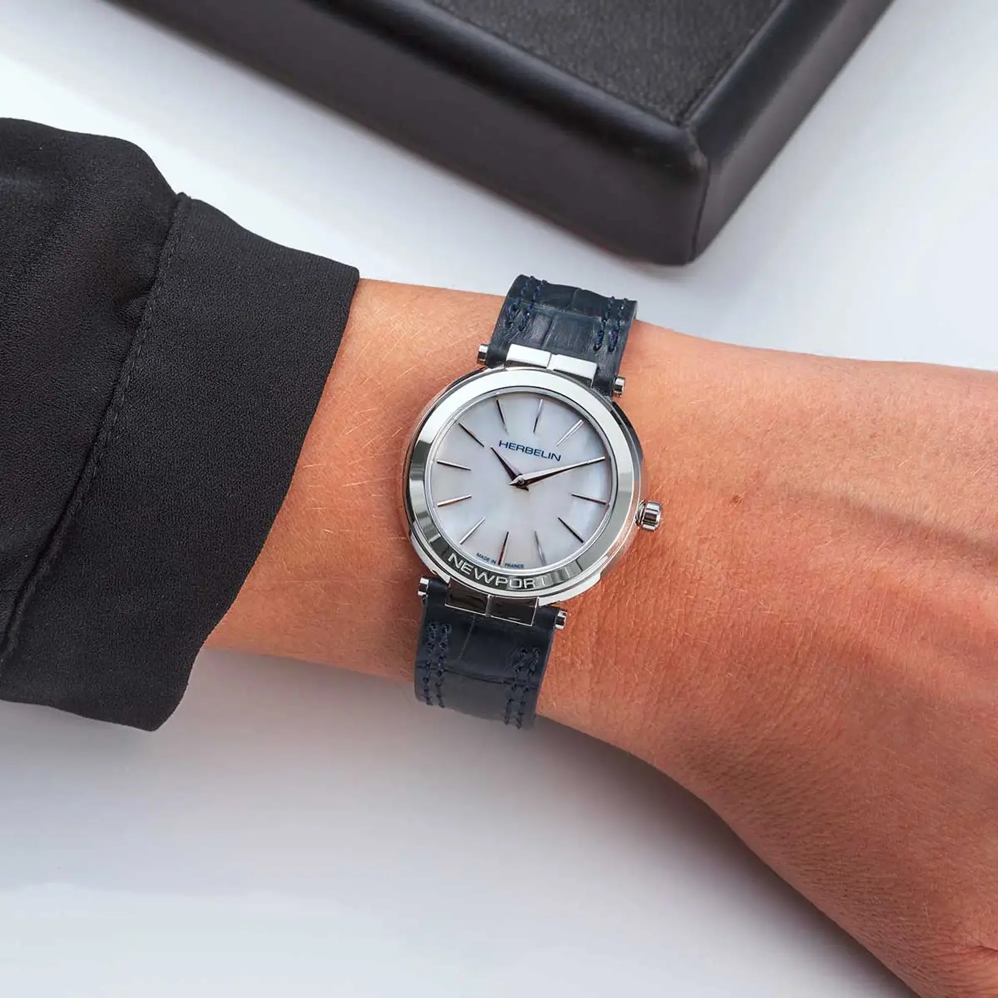 Au poignet féminin, cadran nacre blanche et bracelet cuir visibles